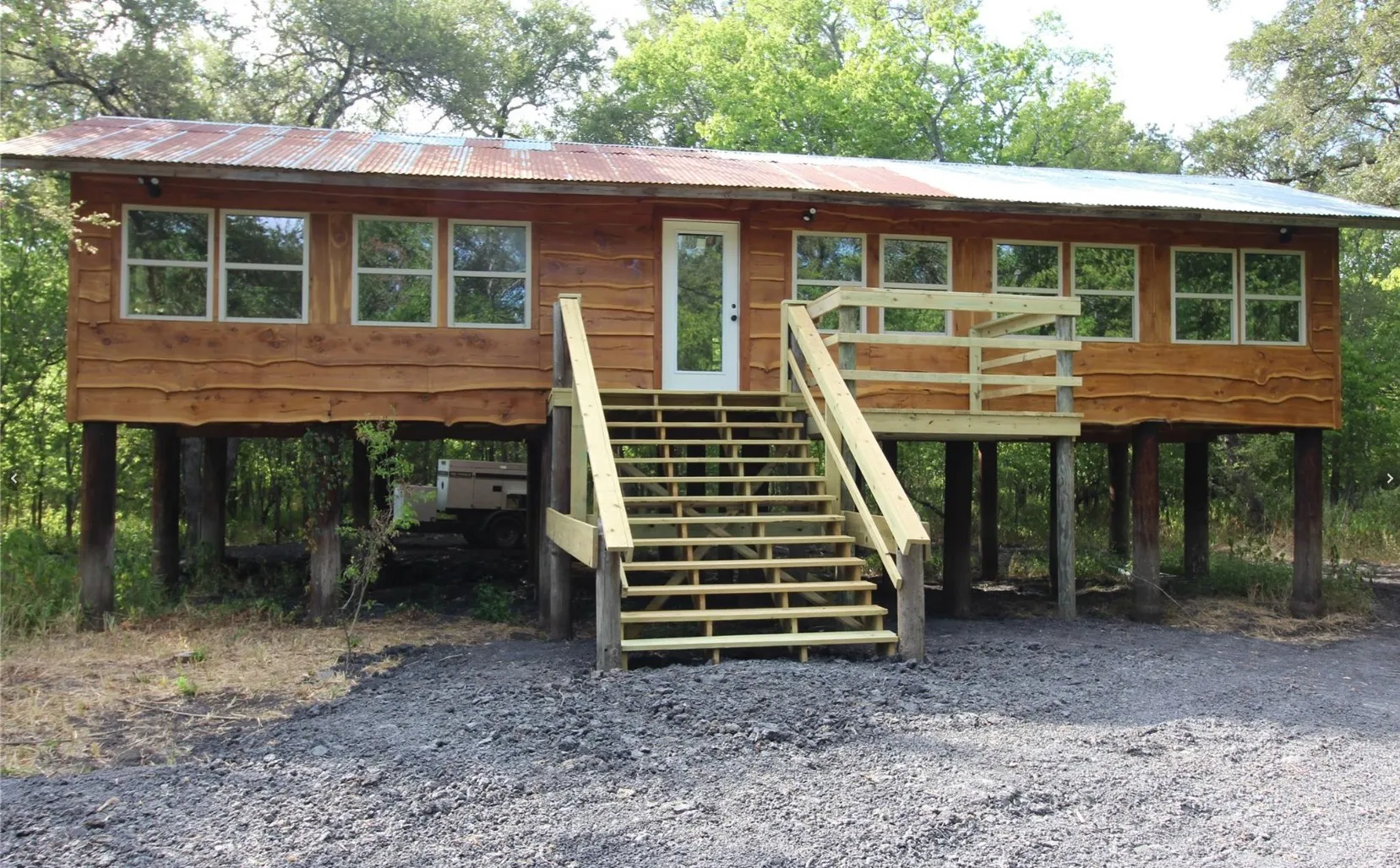 Elevated wood-sided structure featuring a corrugated metal roof