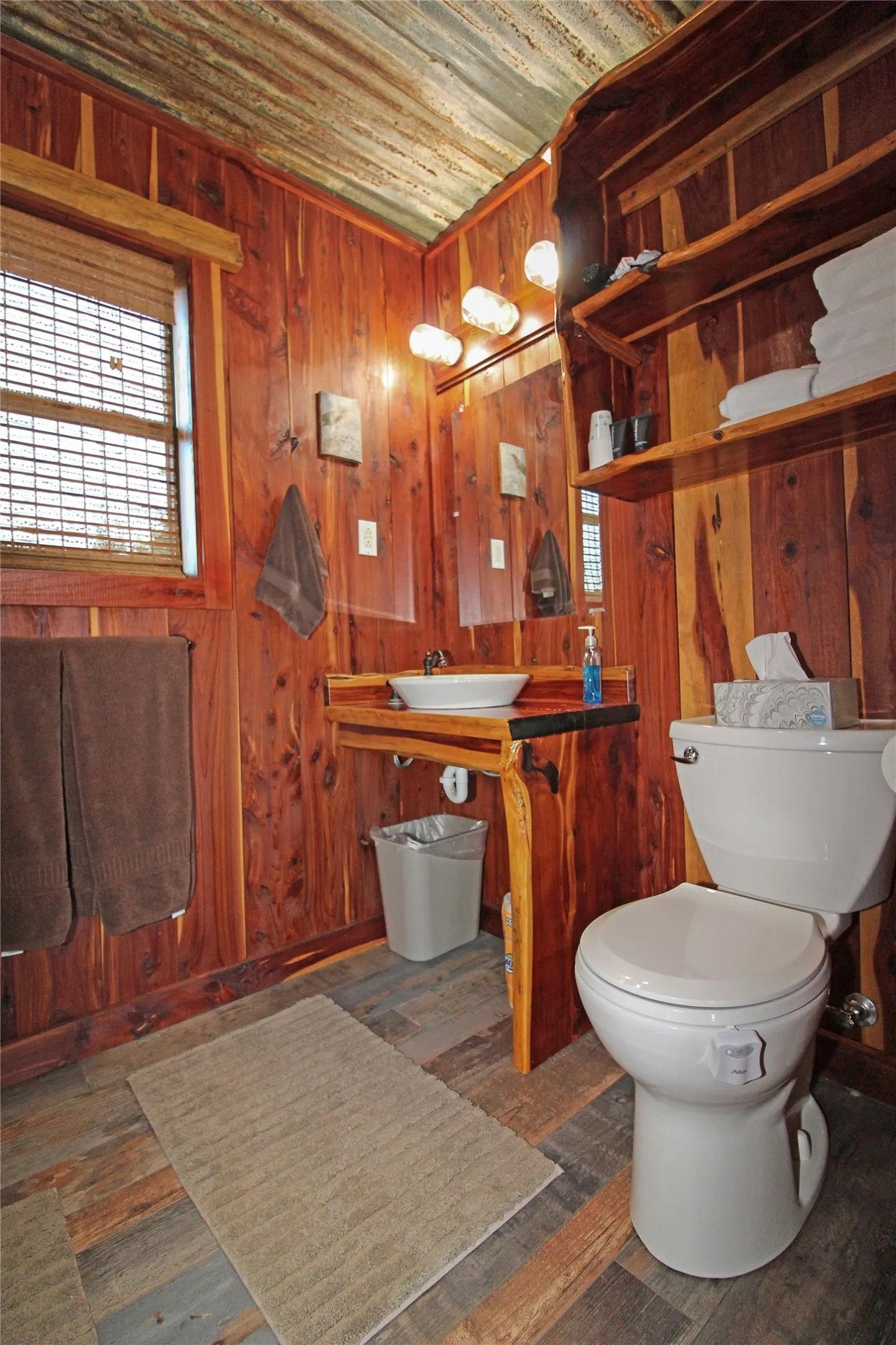 Bathroom featuring wood-paneled walls, a corrugated metal ceiling, and wood-finish flooring