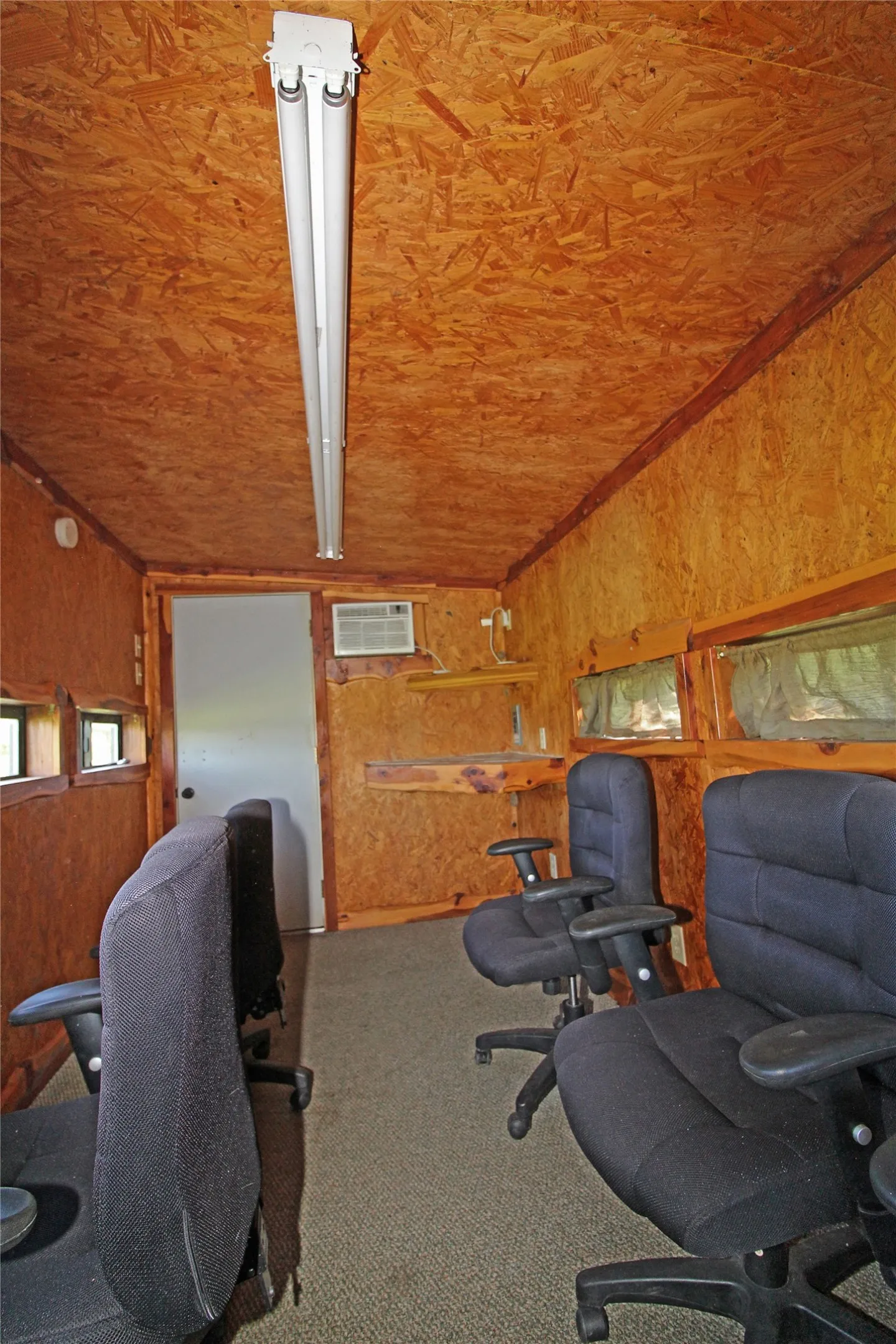 Interior space featuring wood-finish walls and ceiling, carpeted flooring, and a window air conditioning unit