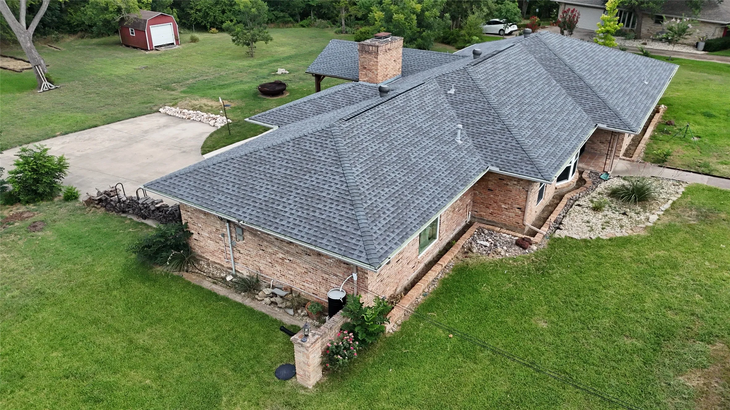 Brick exterior residence featuring a gray shingle roof and a concrete driveway