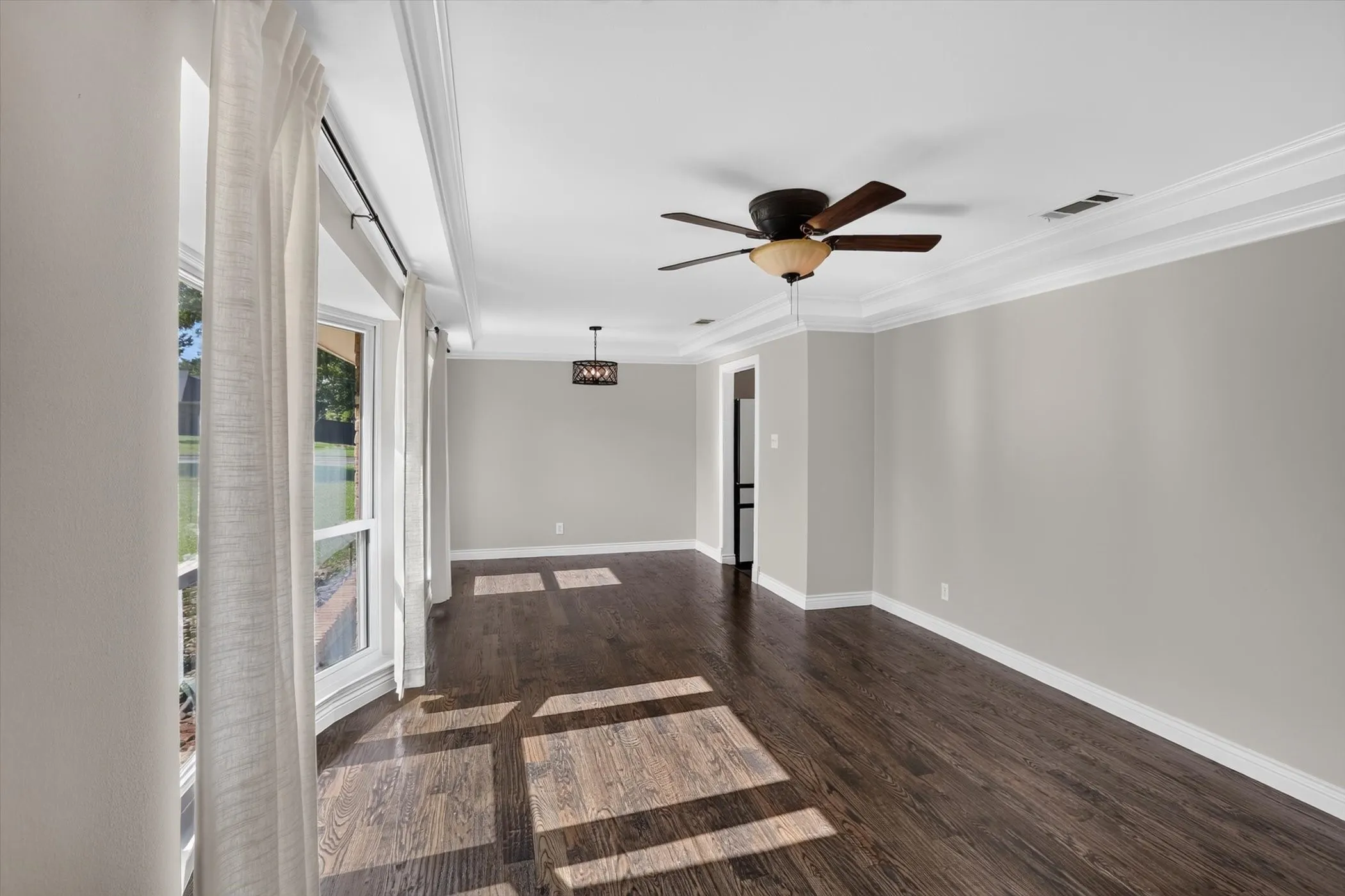Spacious room featuring wood-finish flooring, light gray wall paint, and white crown molding