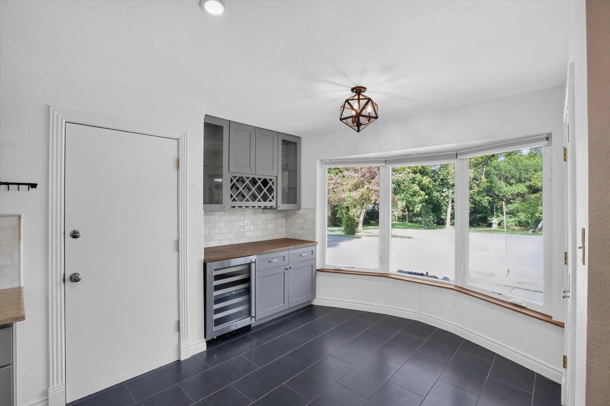 Built-in beverage bar featuring gray cabinetry, a wine refrigerator, and wood-finish countertops
