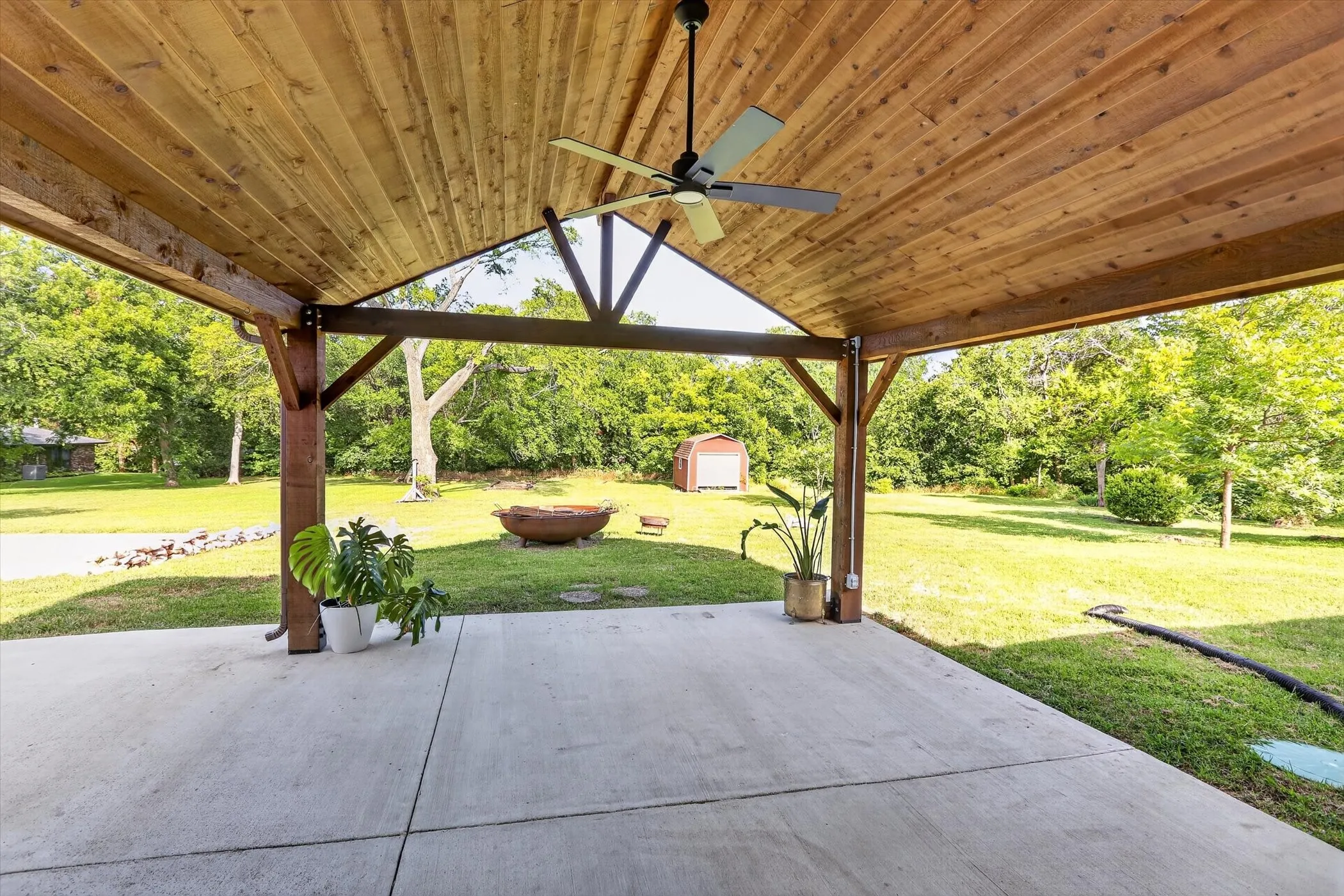 Covered patio featuring a wood-plank ceiling, exposed wood beams, and a ceiling fan
