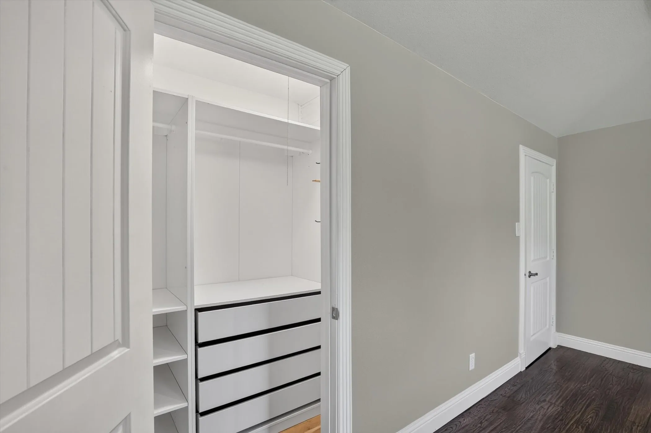Custom closet system featuring multiple shelves, hanging rods, and built-in drawers with black pulls