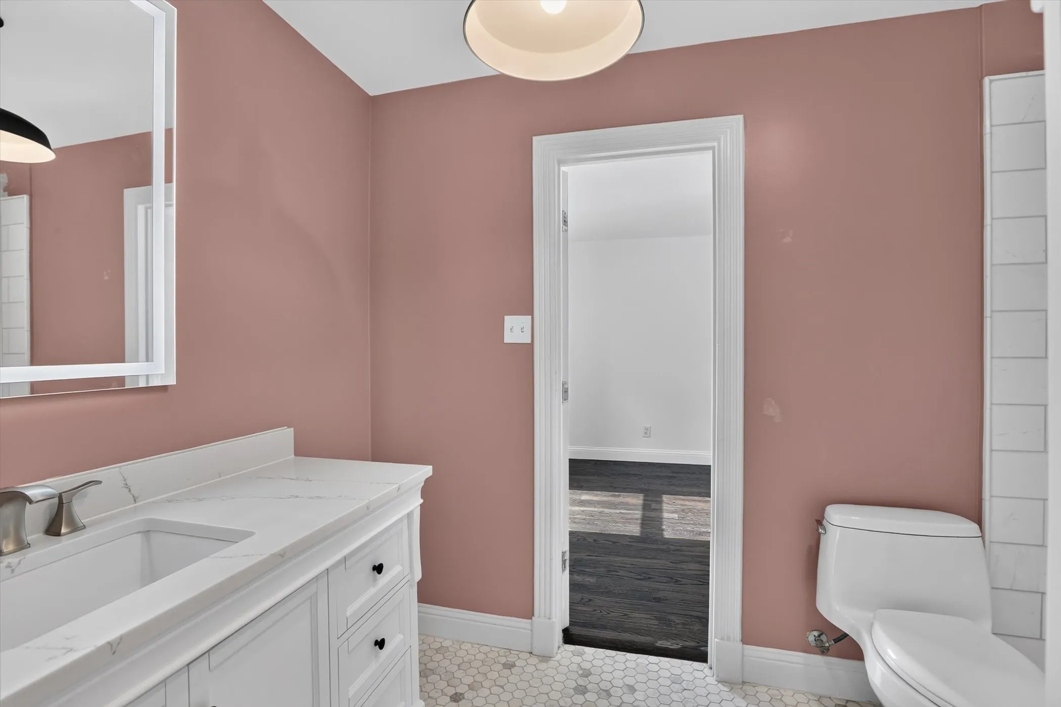 Bathroom featuring a vanity with a white countertop and undermount sink, brushed nickel faucet, and a wall-mounted mirror