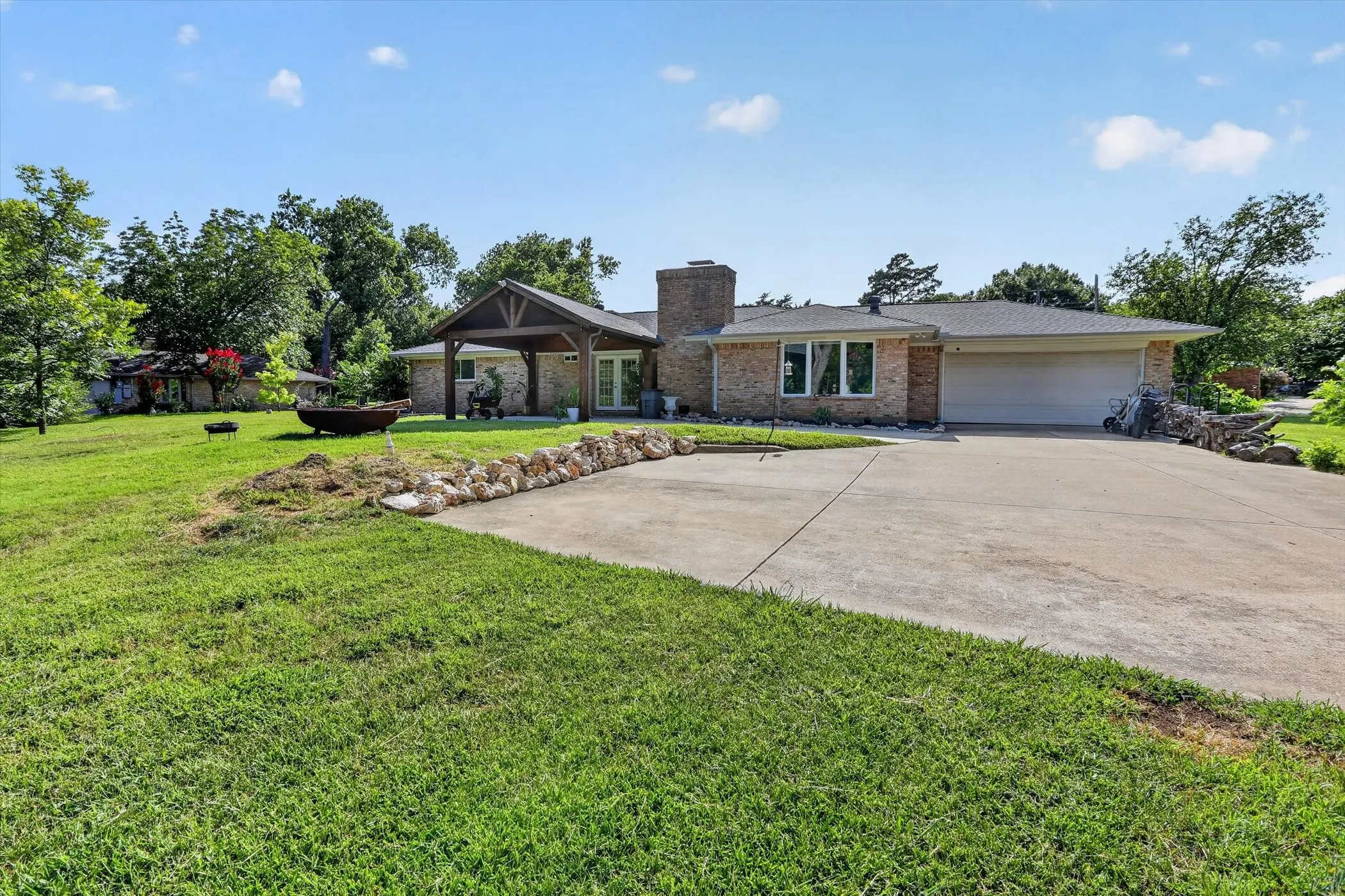 Brick exterior with a covered entryway, attached garage, and a concrete driveway