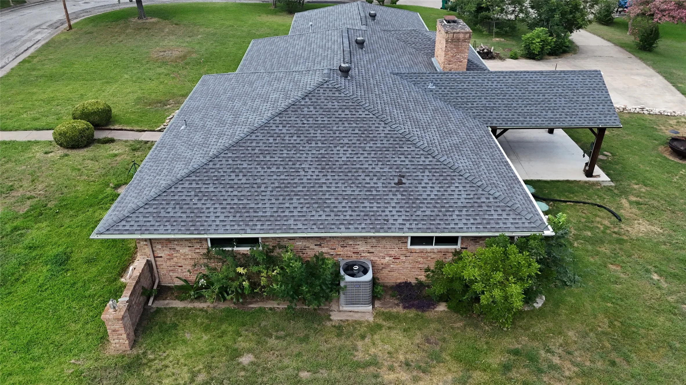 Gable roofline with asphalt shingles, featuring a brick exterior and covered patio