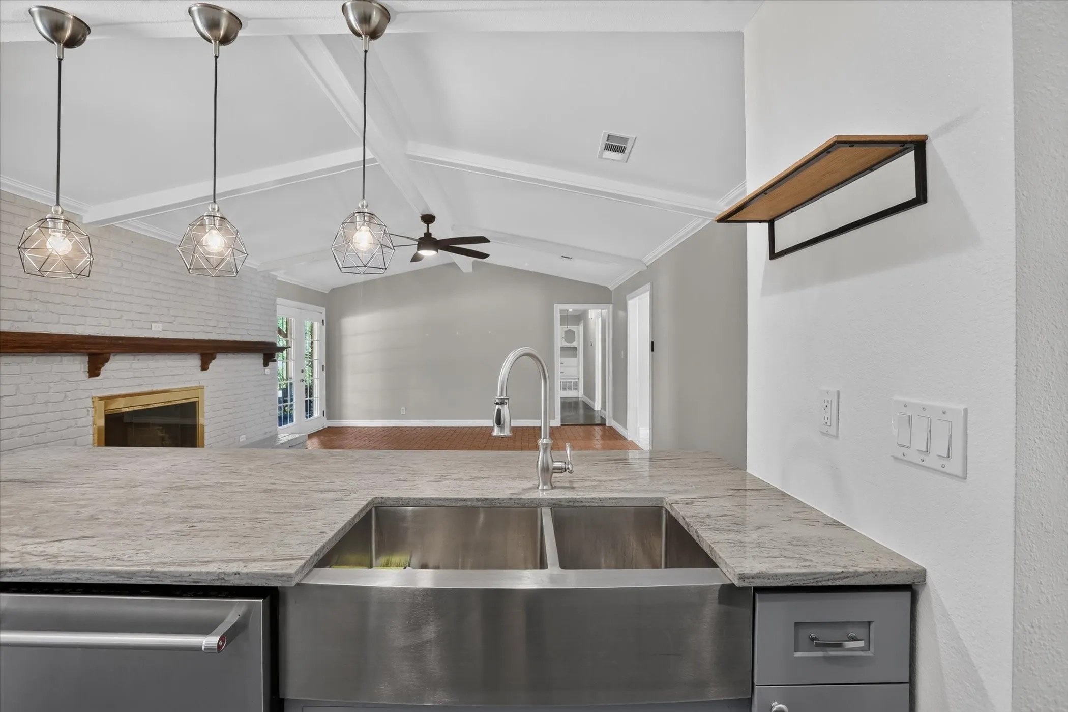 Kitchen island featuring a double basin stainless steel farmhouse sink, a stainless steel faucet, and a light-toned stone countertop