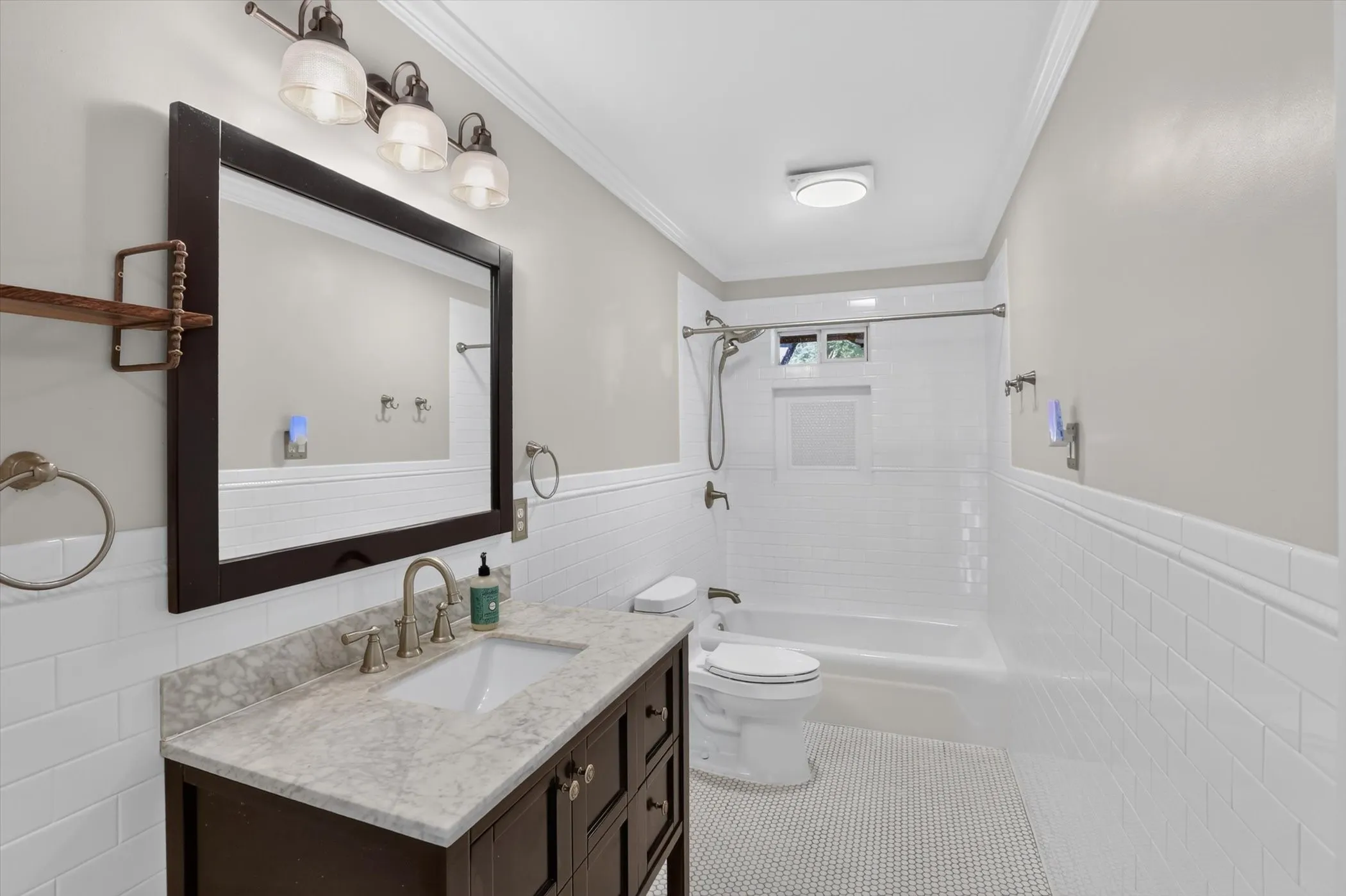 Bathroom featuring a dark wood vanity with a light-toned countertop, an integrated sink, and a framed mirror