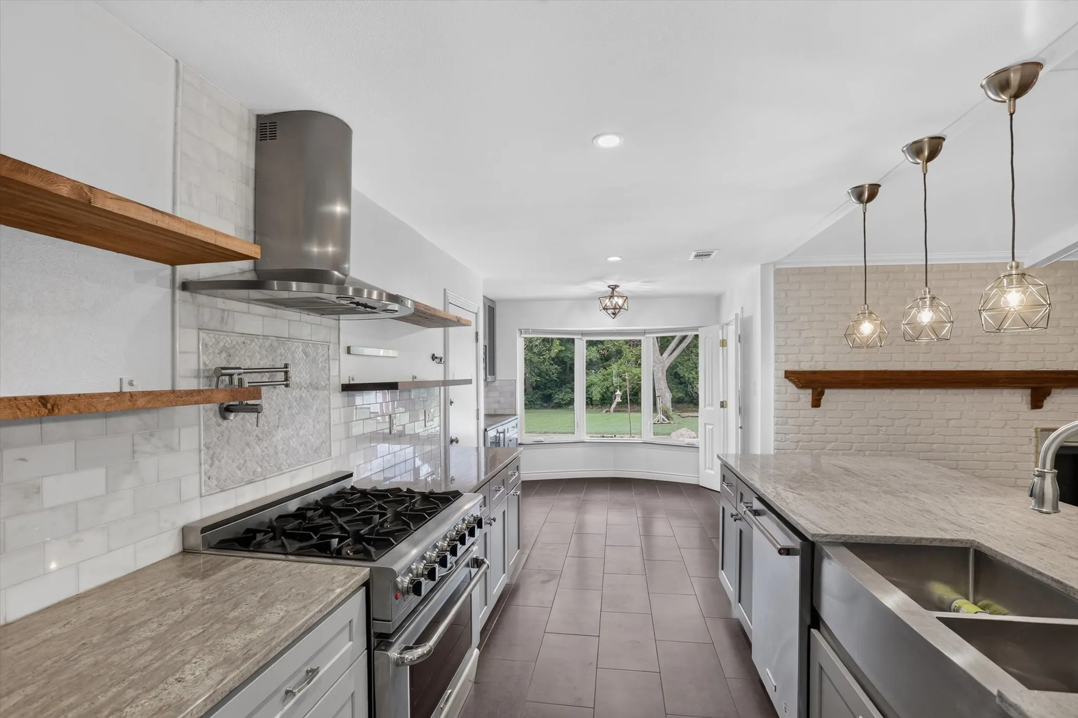Gourmet kitchen with professional-grade stainless steel range, custom range hood, pot filler, light gray cabinetry, and stone countertops