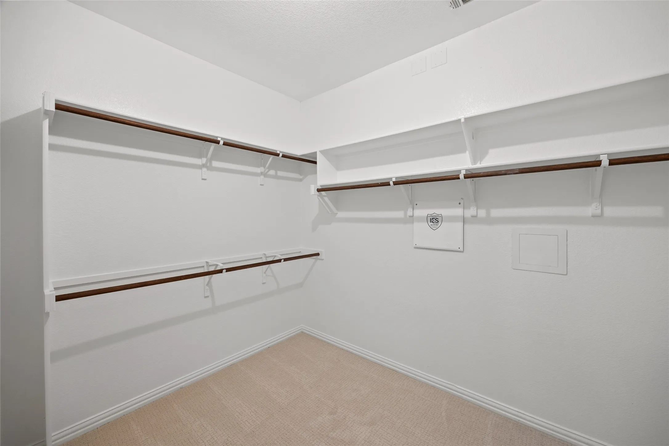 Spacious walk-in closet featuring white shelving and wood-finish hanging rods