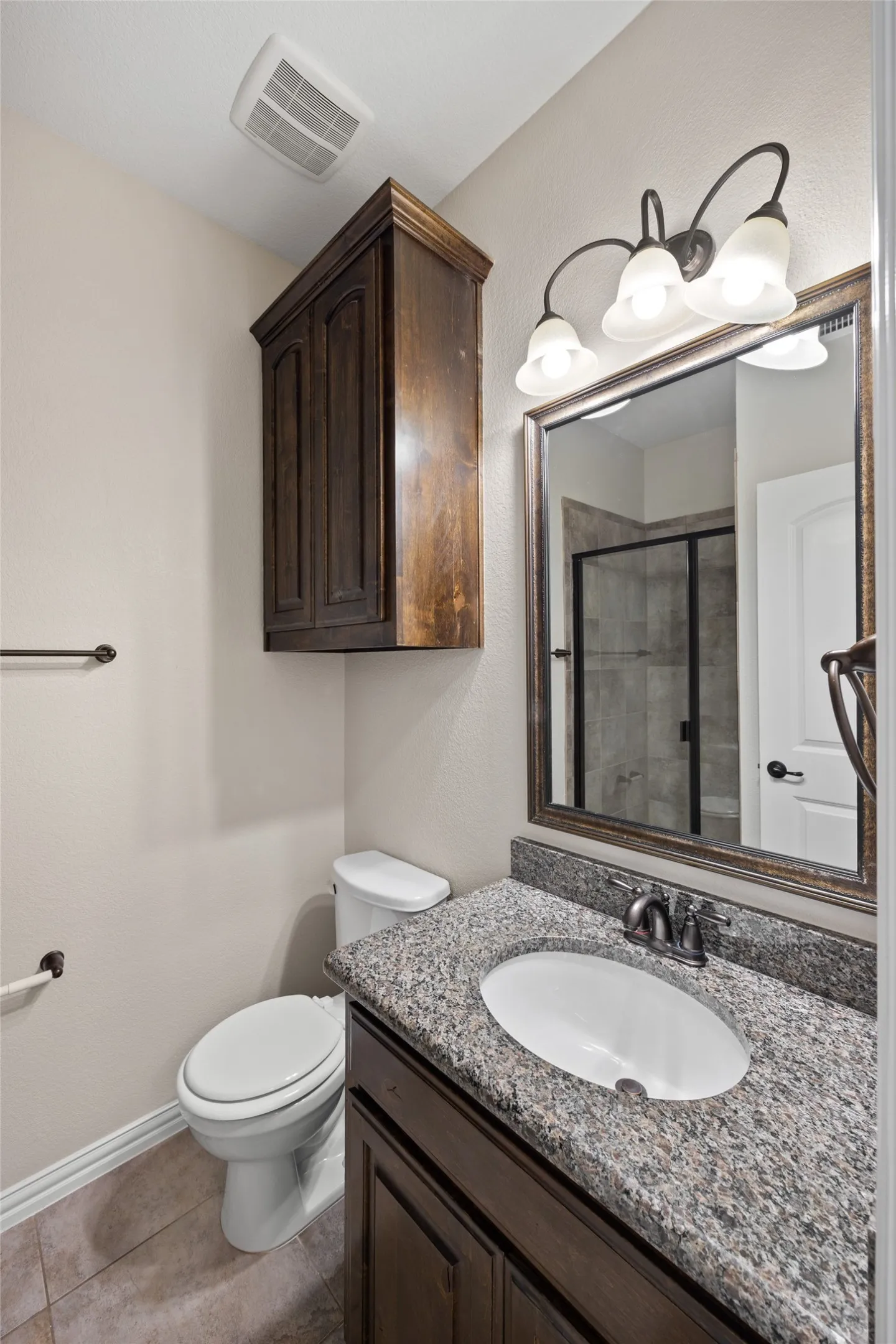 Bathroom featuring a vanity with an undermount sink, granite countertop, and dark wood cabinetry