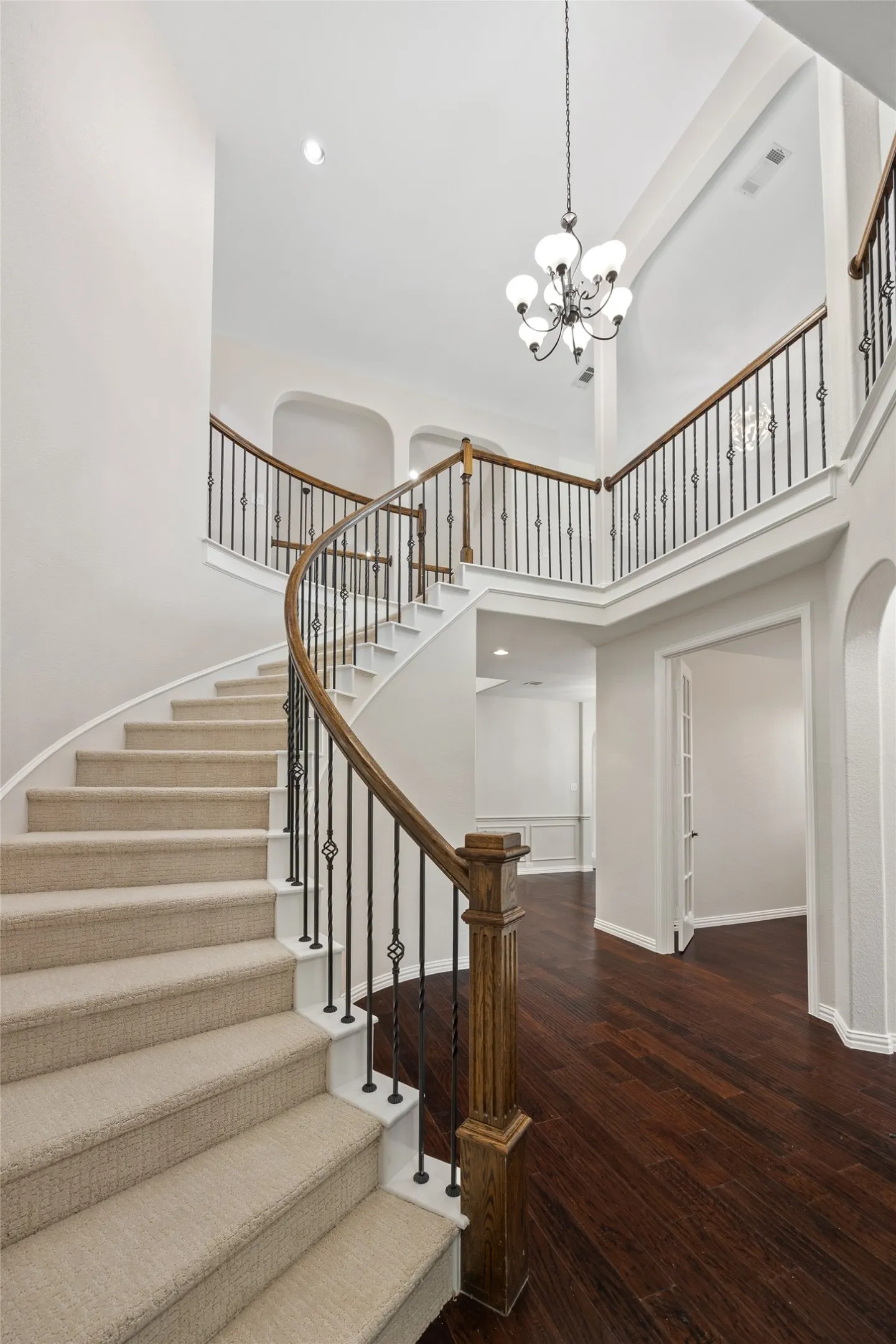 Grand entryway featuring a curved staircase with carpeted treads, wrought iron balusters, and a rich wood-finish handrail