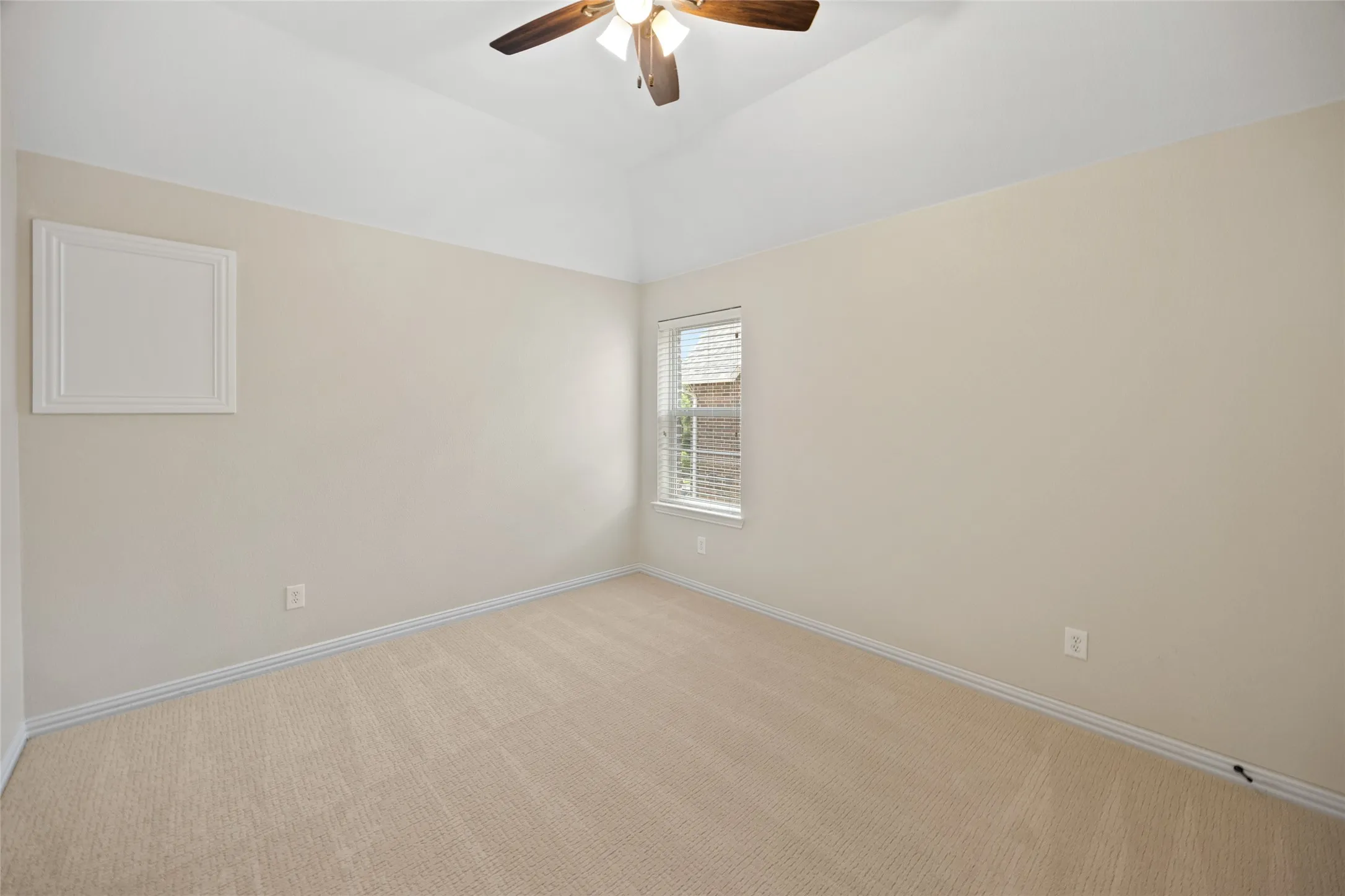 Room featuring neutral-toned carpeting and walls, a vaulted ceiling, and a ceiling fan with integrated lighting