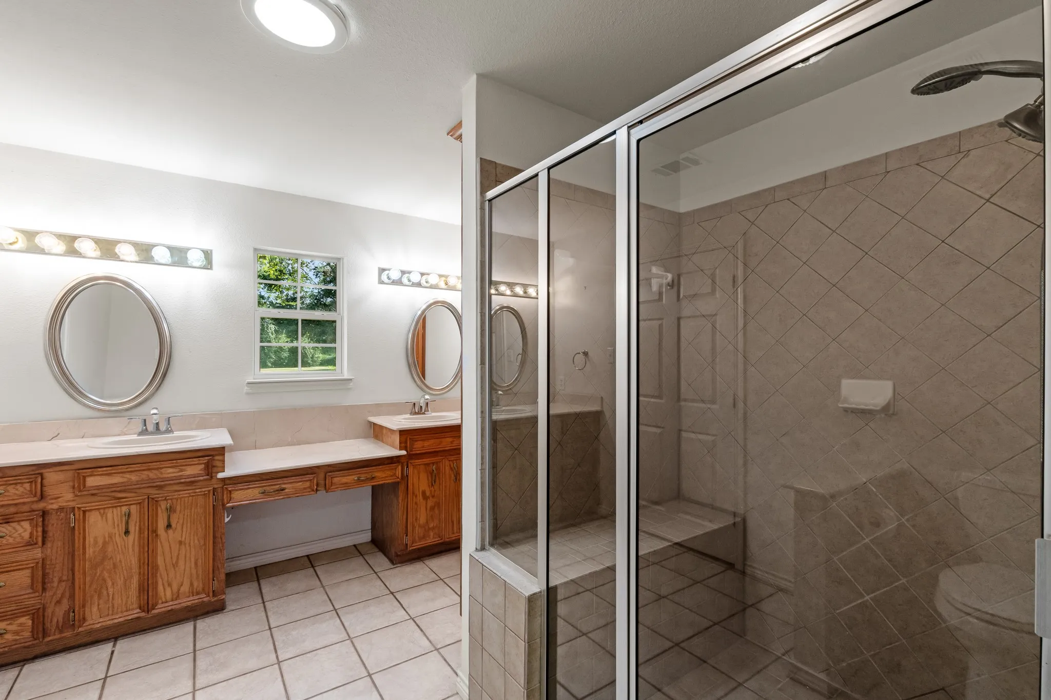 Primary bath featuring a walk-in tile shower, double vanity, and built-in linen storage.