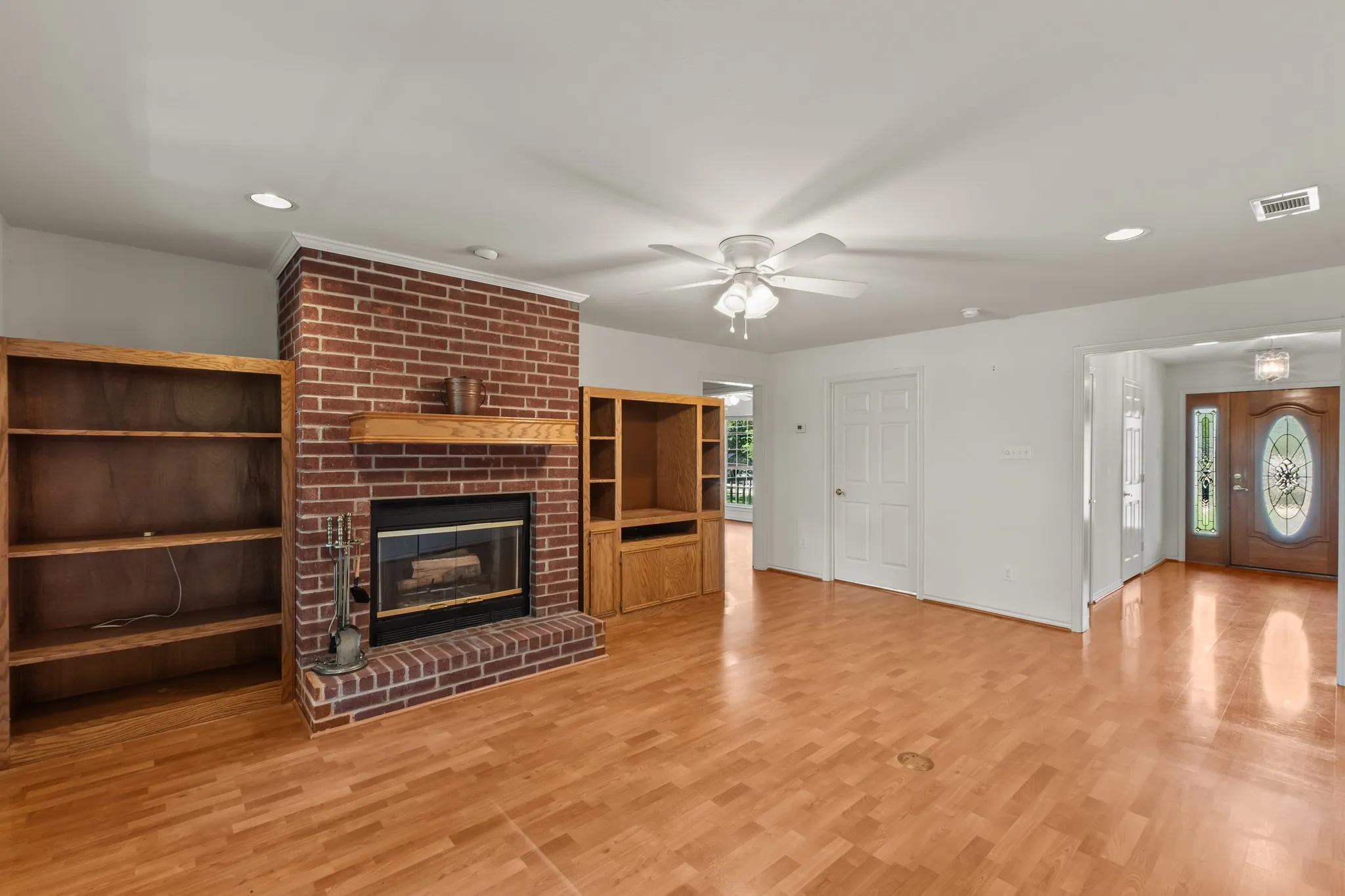 Inviting living room featuring durable laminate flooring and a beautiful red brick fireplace. Cabinets are not attached and can be removed if desired.