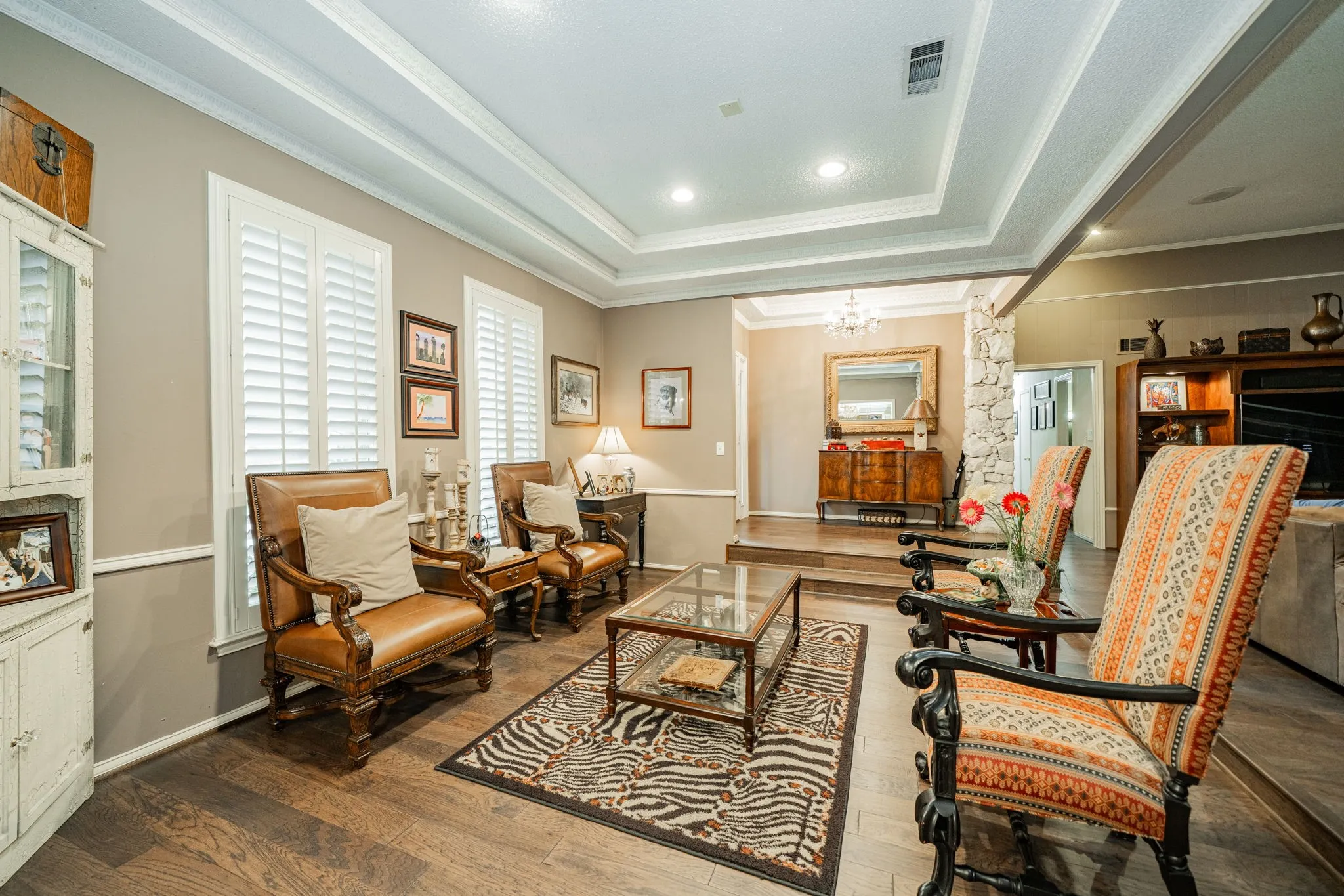 Living area featuring a raised ceiling, wood finished floors, a chandelier, ornamental molding, and recessed lighting