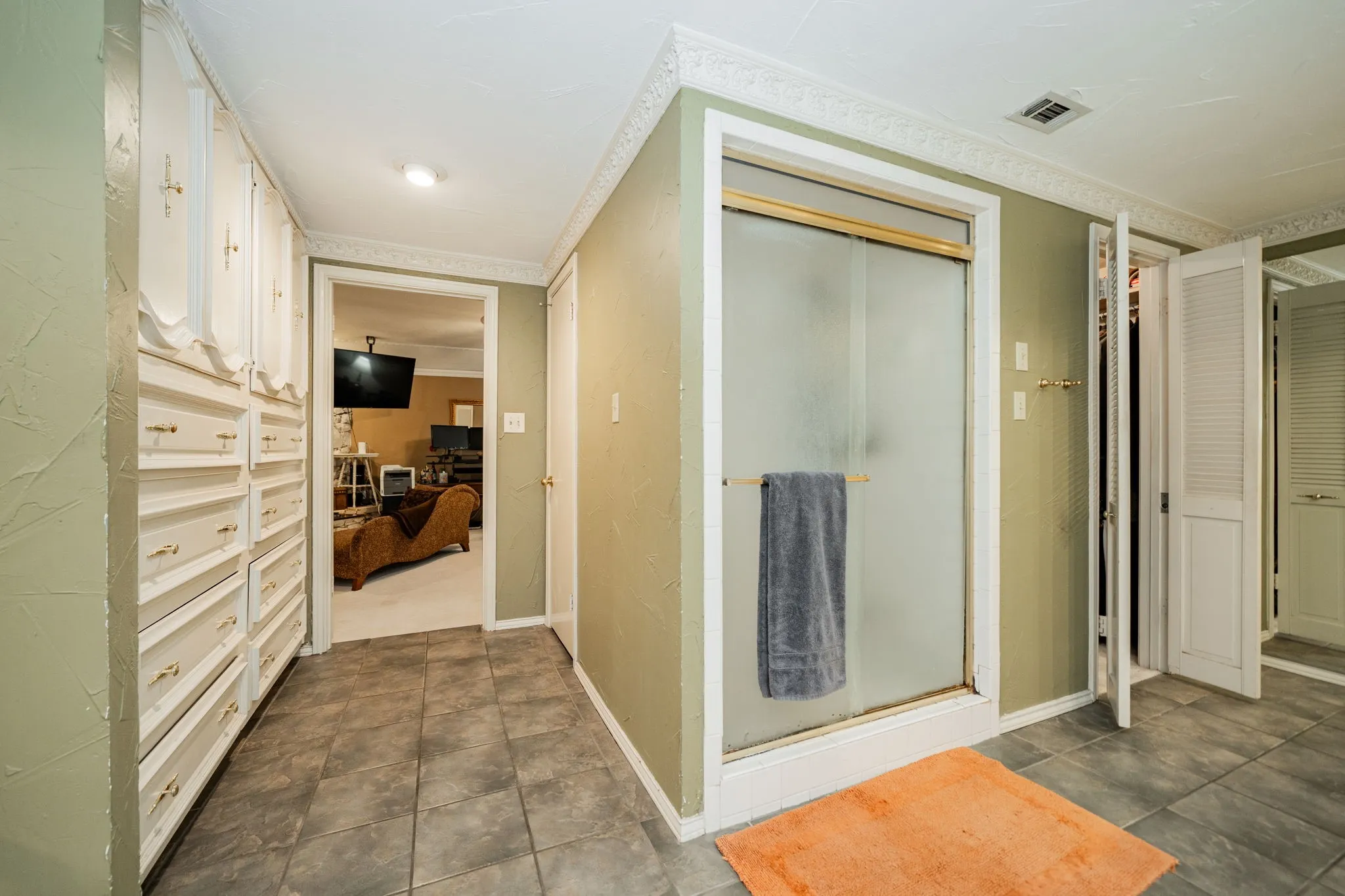Bath featuring dark tile patterned floors and crown molding