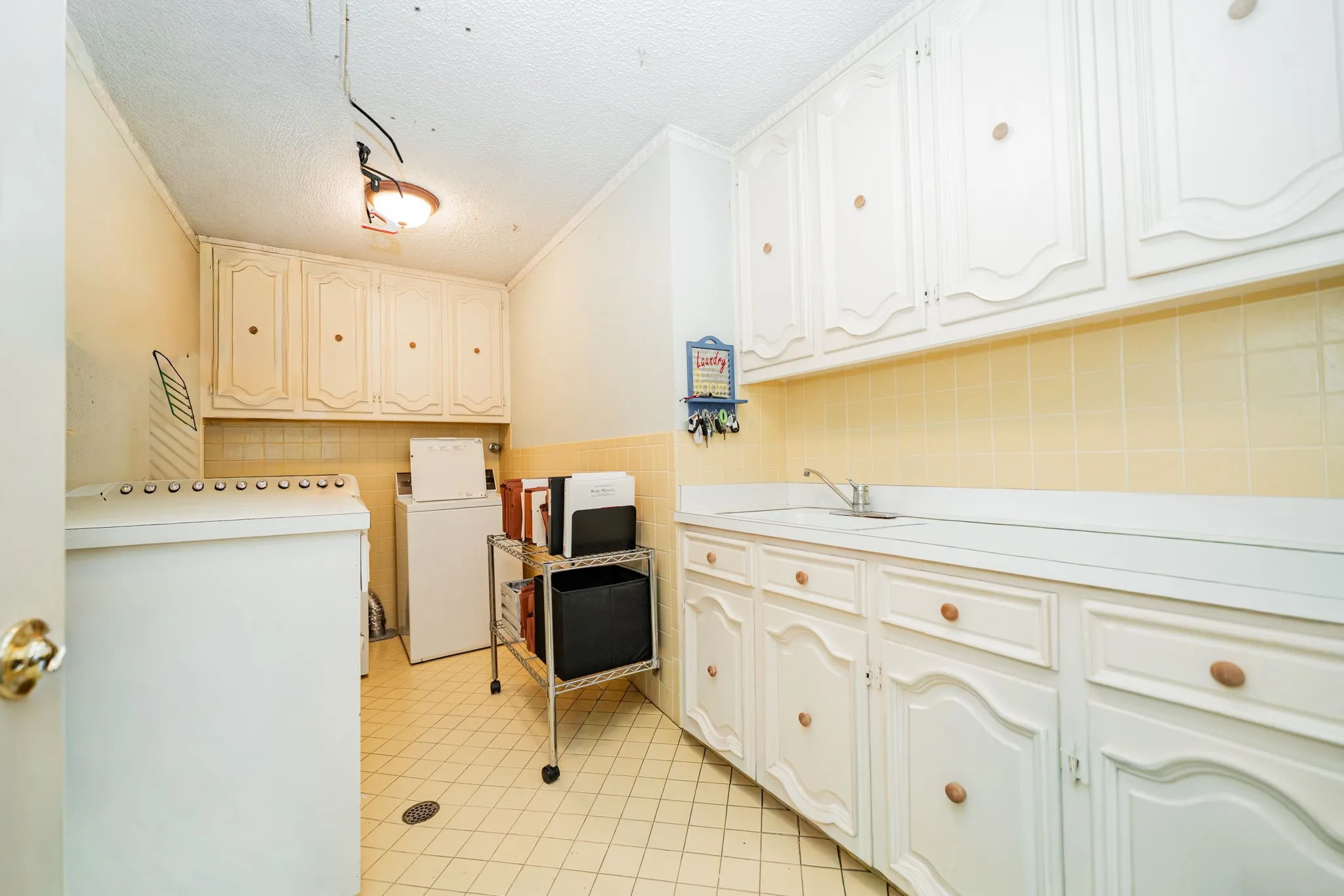 Washroom featuring a textured ceiling, washer / dryer, crown molding, and light tile patterned flooring