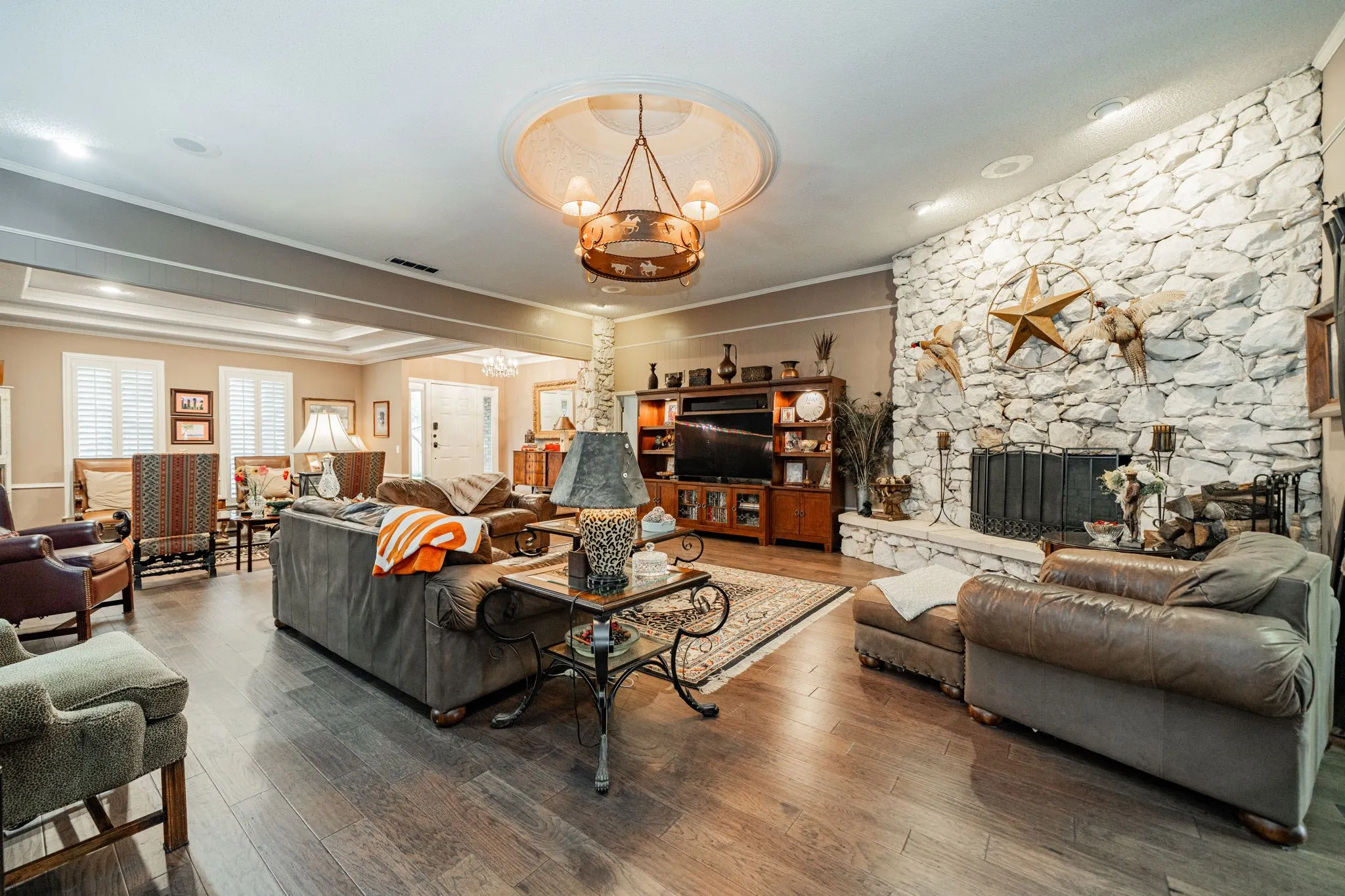 Living area with crown molding, wood finished floors, a fireplace, and a chandelier
