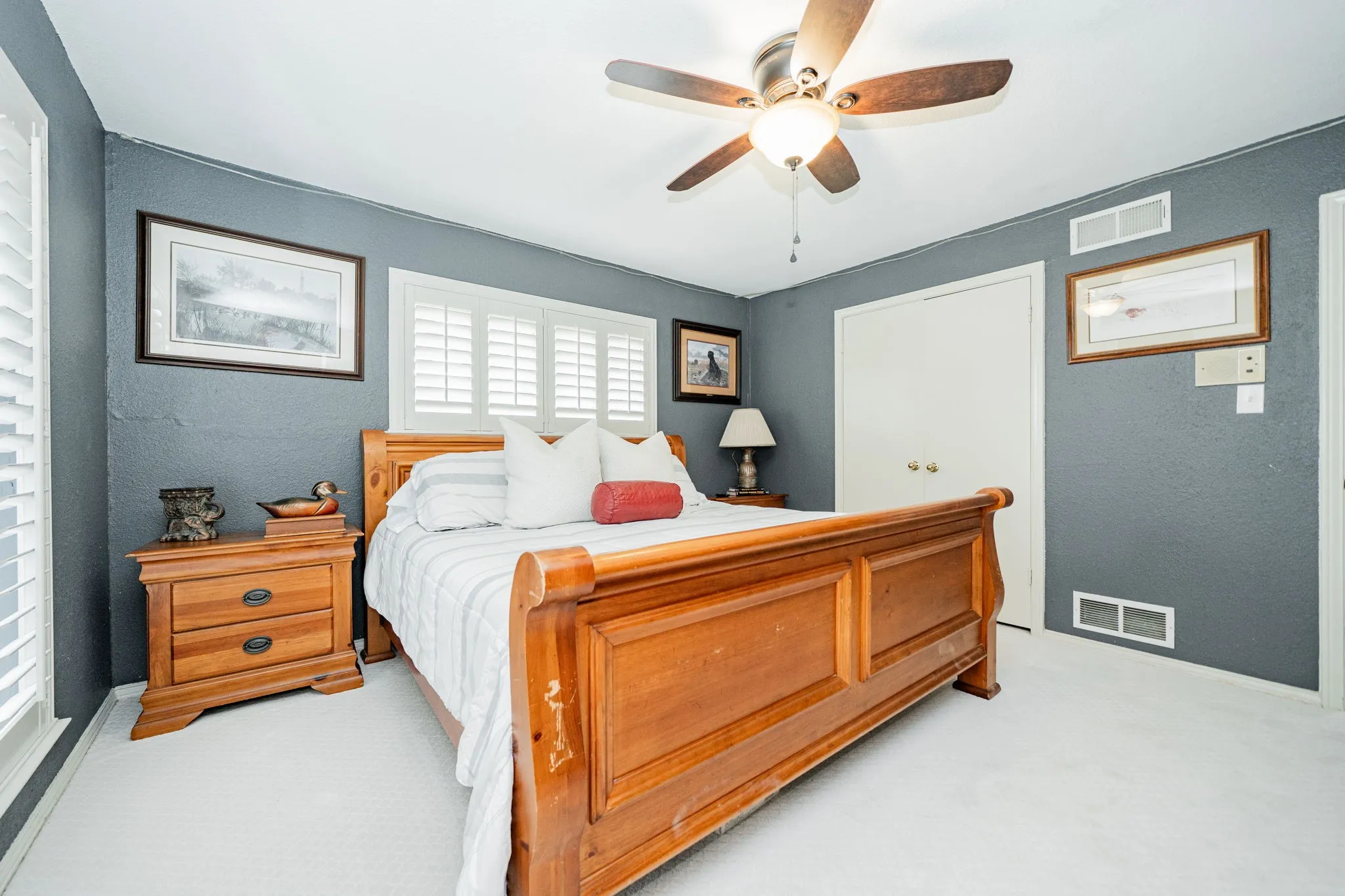 Bedroom with a textured wall, light carpet, and a ceiling fan
