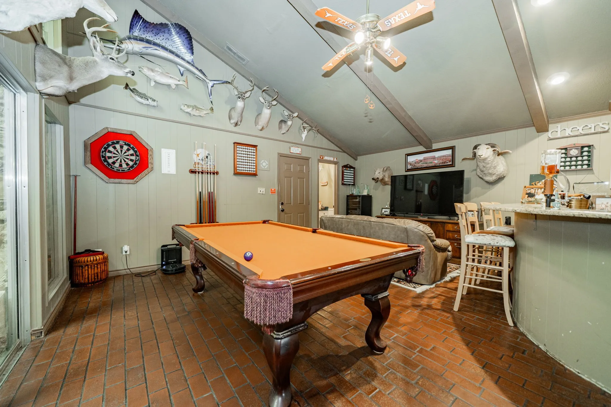 Recreation room with billiards, brick flooring, a dry bar, wood walls, and beam ceiling
