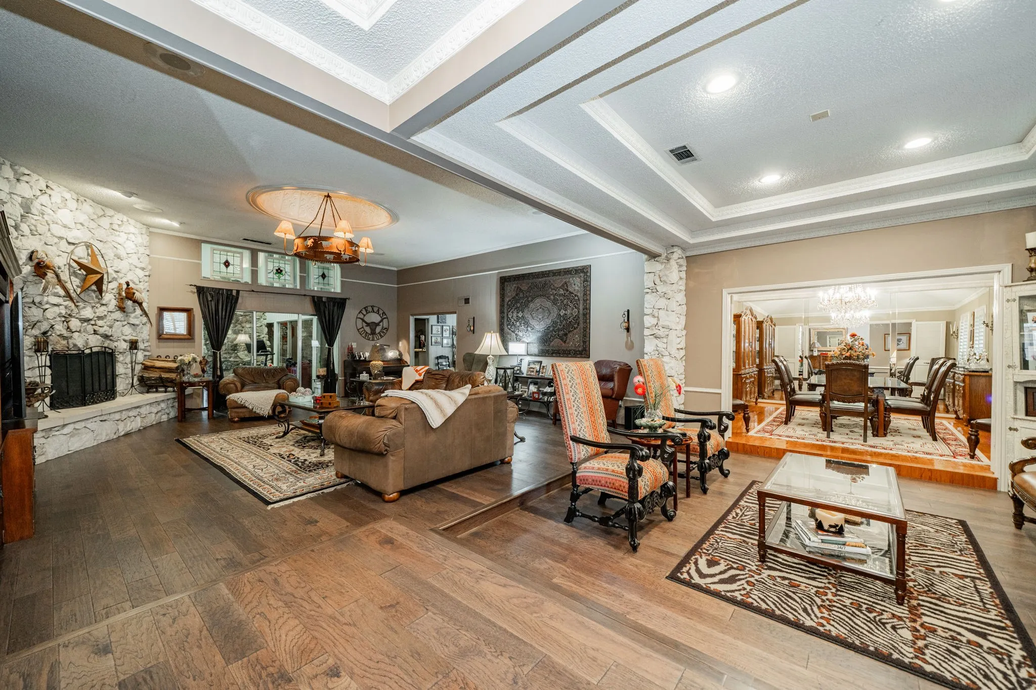 Living room with a chandelier, a fireplace, hardwood / wood-style flooring, ornamental molding, and a textured ceiling
