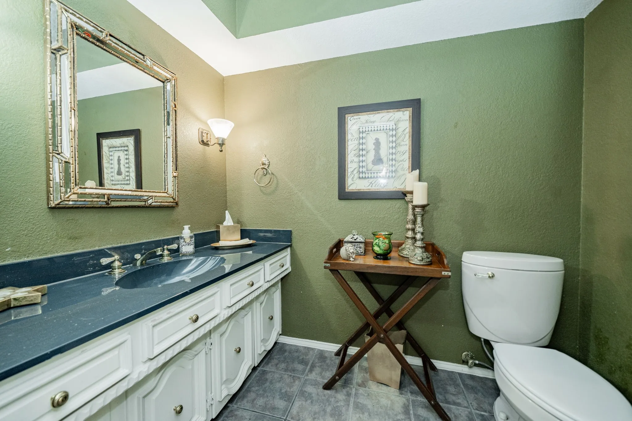 Half bath with a textured wall, vanity, and dark tile patterned flooring
