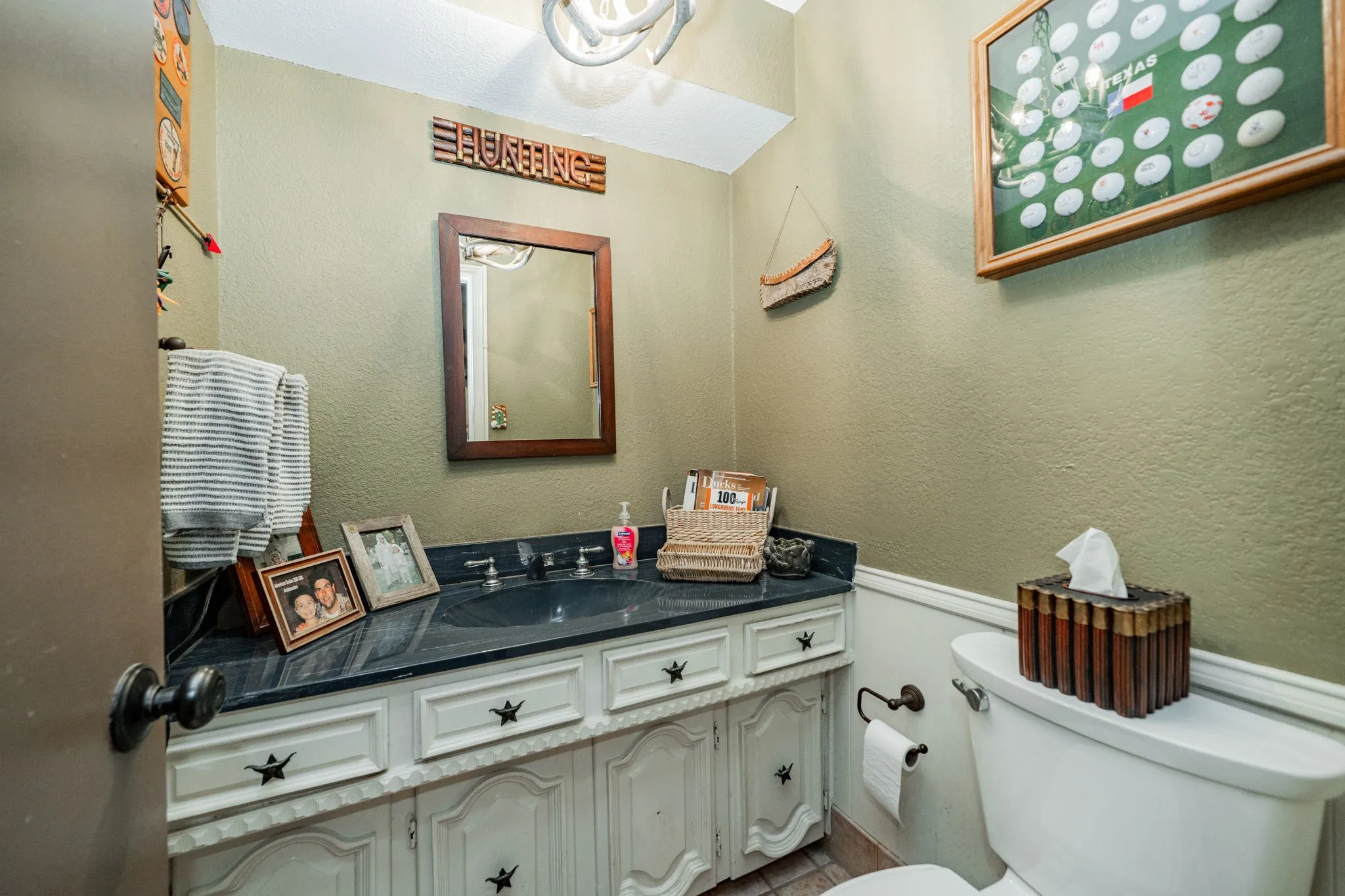 Half bath with a textured wall, vanity, and wainscoting