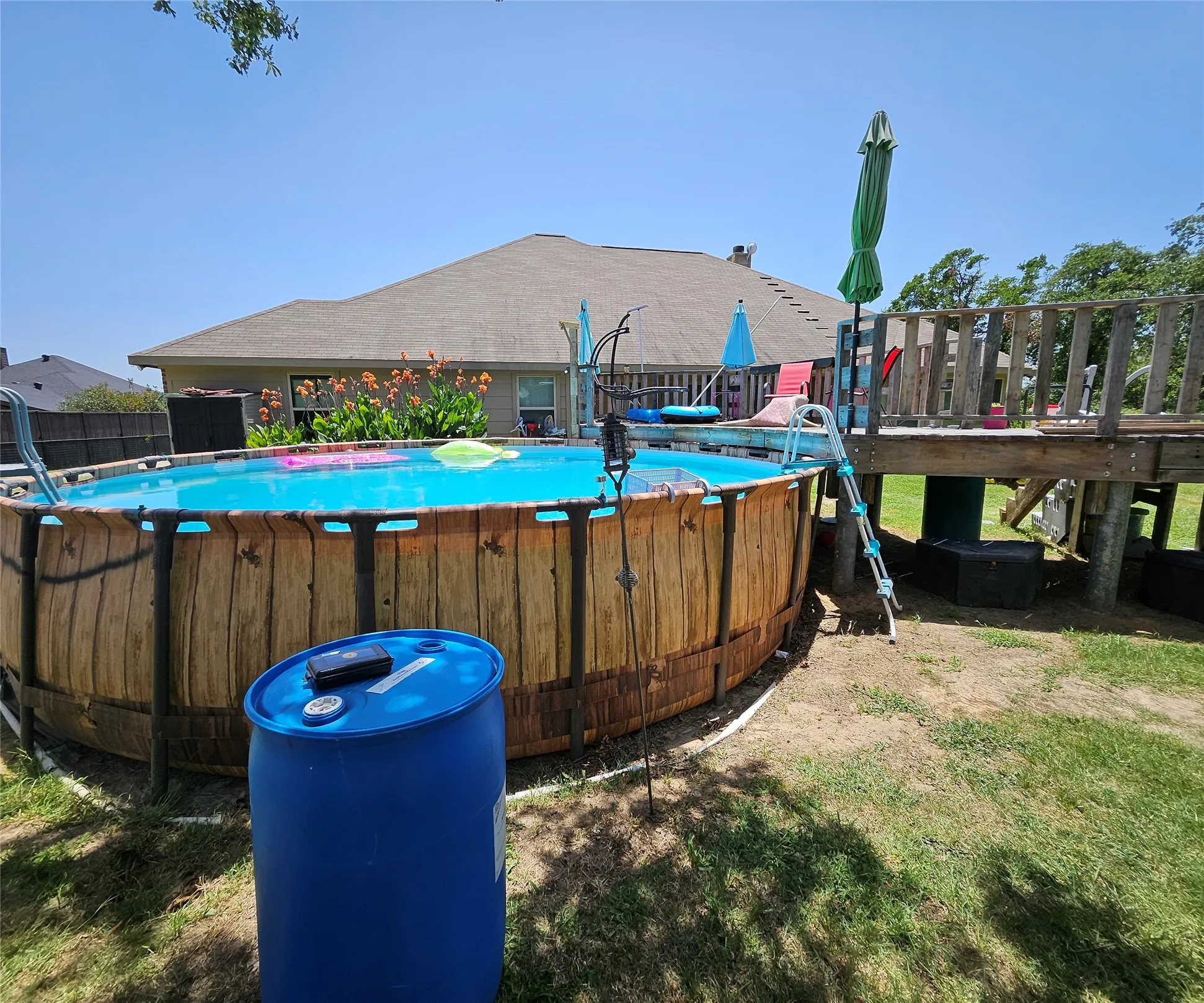 Above-ground pool with wood-finish siding, accompanied by a multi-level wooden deck