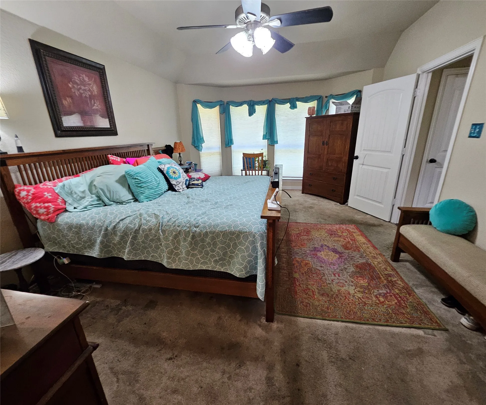 Spacious room featuring vaulted ceilings, a ceiling fan with integrated lighting, multiple windows, and light-toned wall finishes