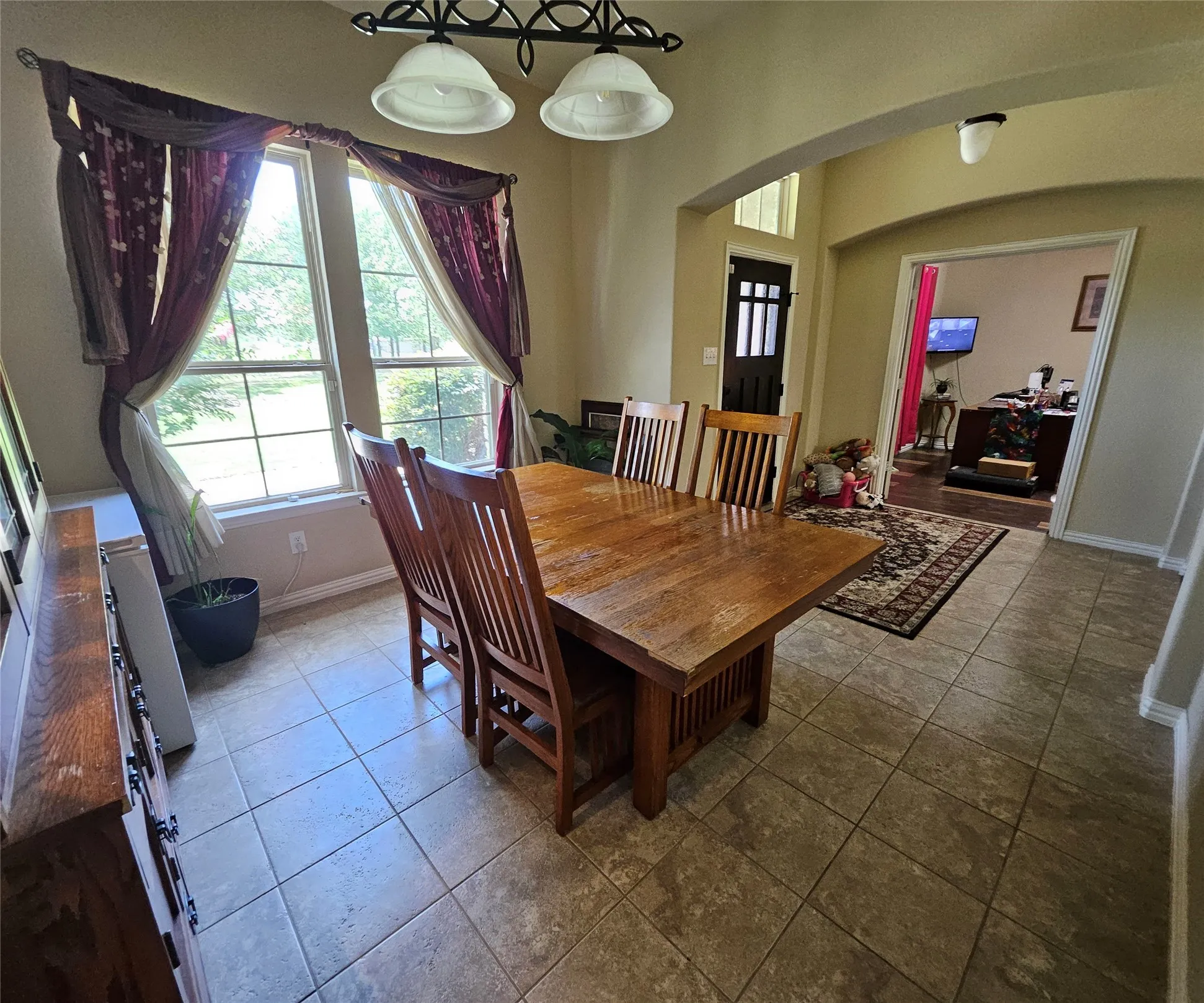 Dining area featuring tile flooring, a large window with exterior views, and an arched entry