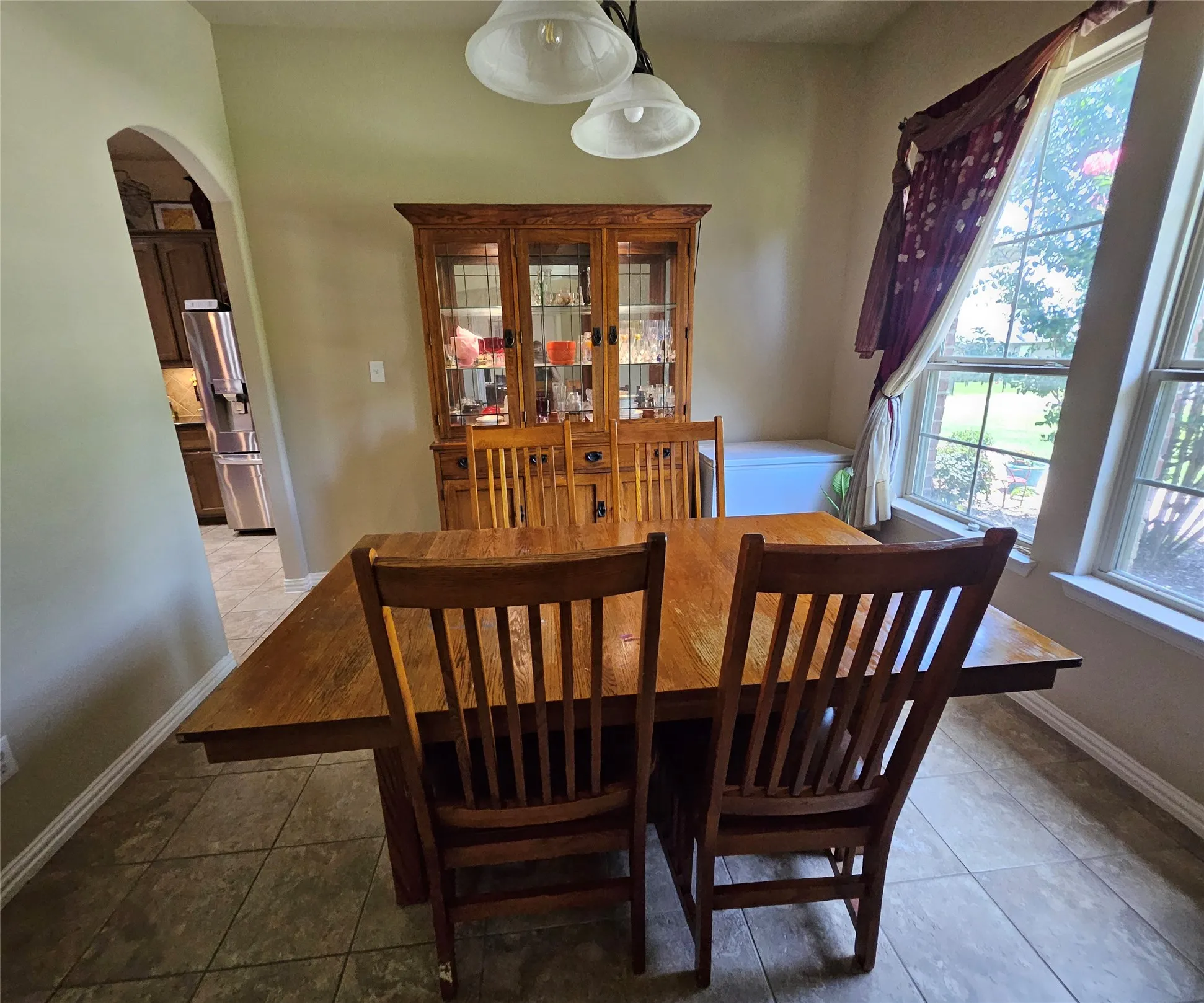 Dining space featuring tile flooring, a multi-pane window, and an arched entryway