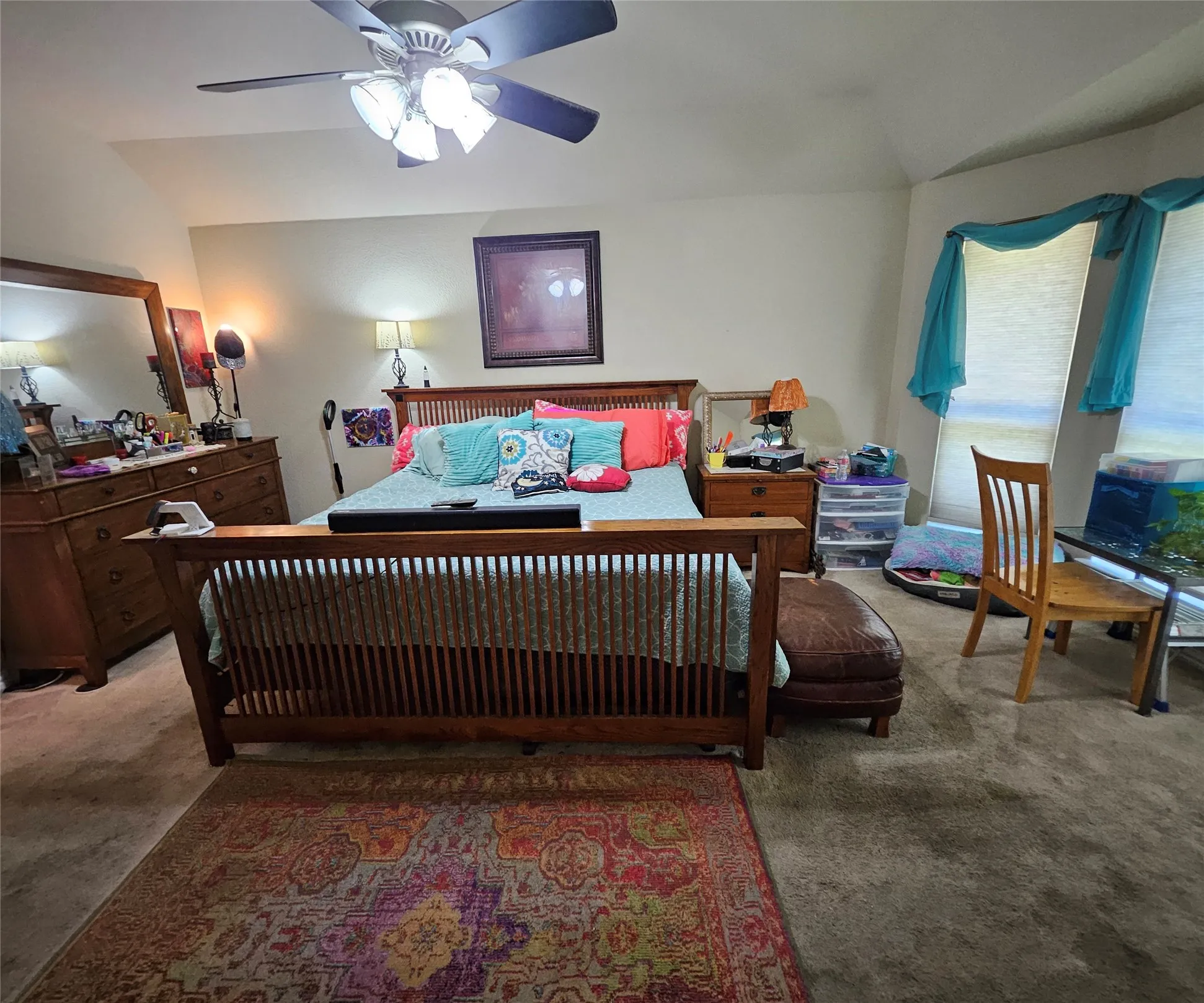 Carpeted bedroom featuring a ceiling fan with integrated lighting, multiple windows with roller shades, and ample wall space