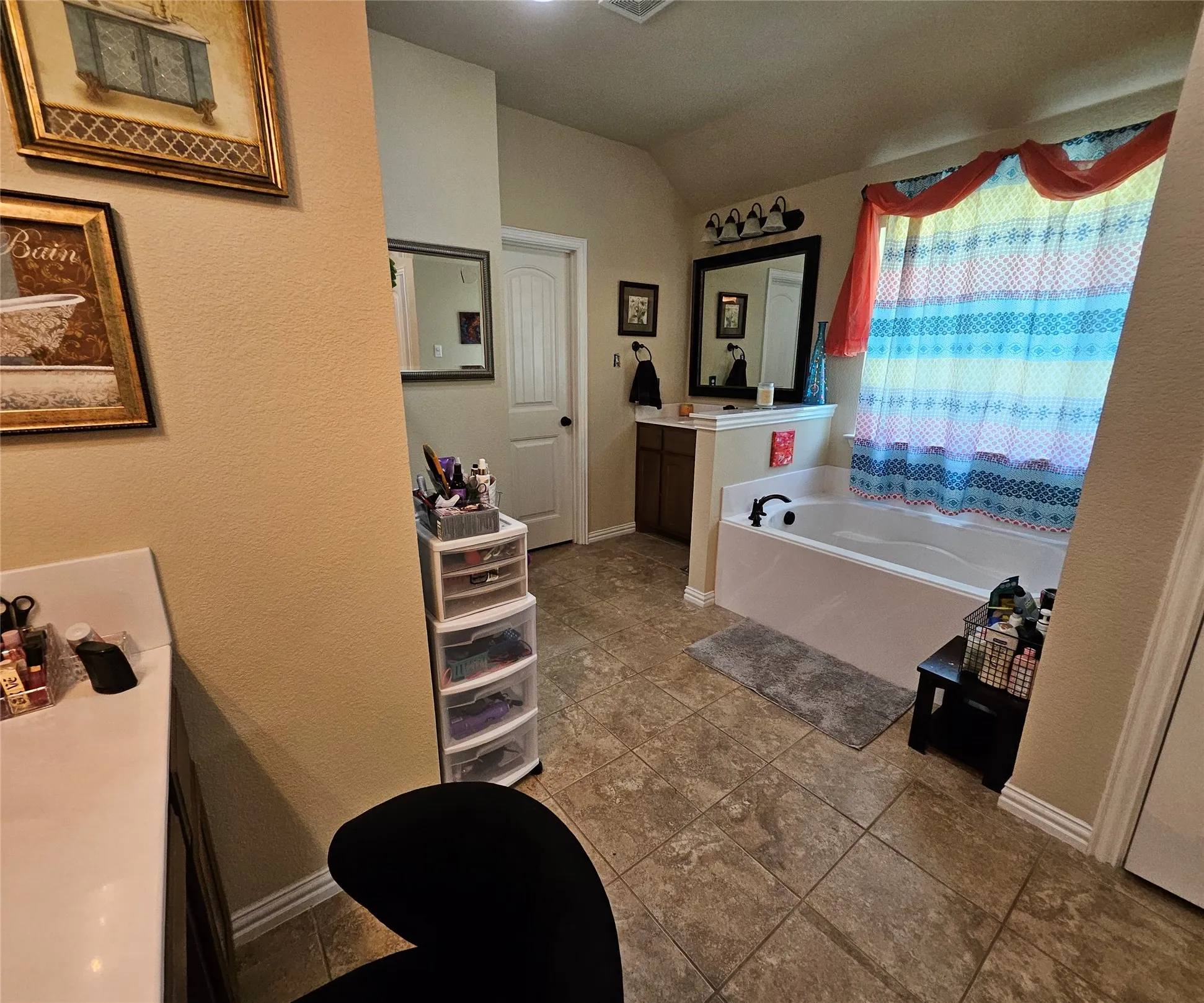 Spacious bathroom featuring an integrated soaking tub, dual vanity areas, wood-finish cabinetry, and tiled flooring