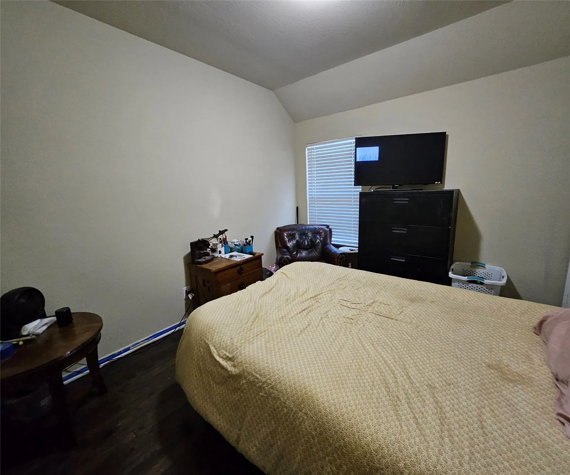 Bedroom featuring wood-finish flooring, a window with horizontal blinds, and neutral-toned walls