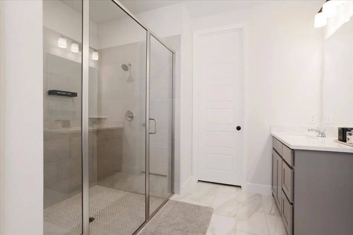 Primary bath features an extended shower and two separate vanities.