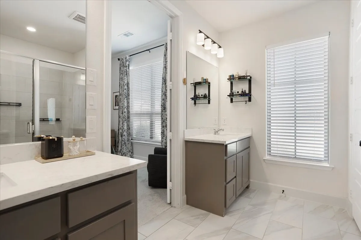 The primary bath has separate vanities and beautiful tile floors.