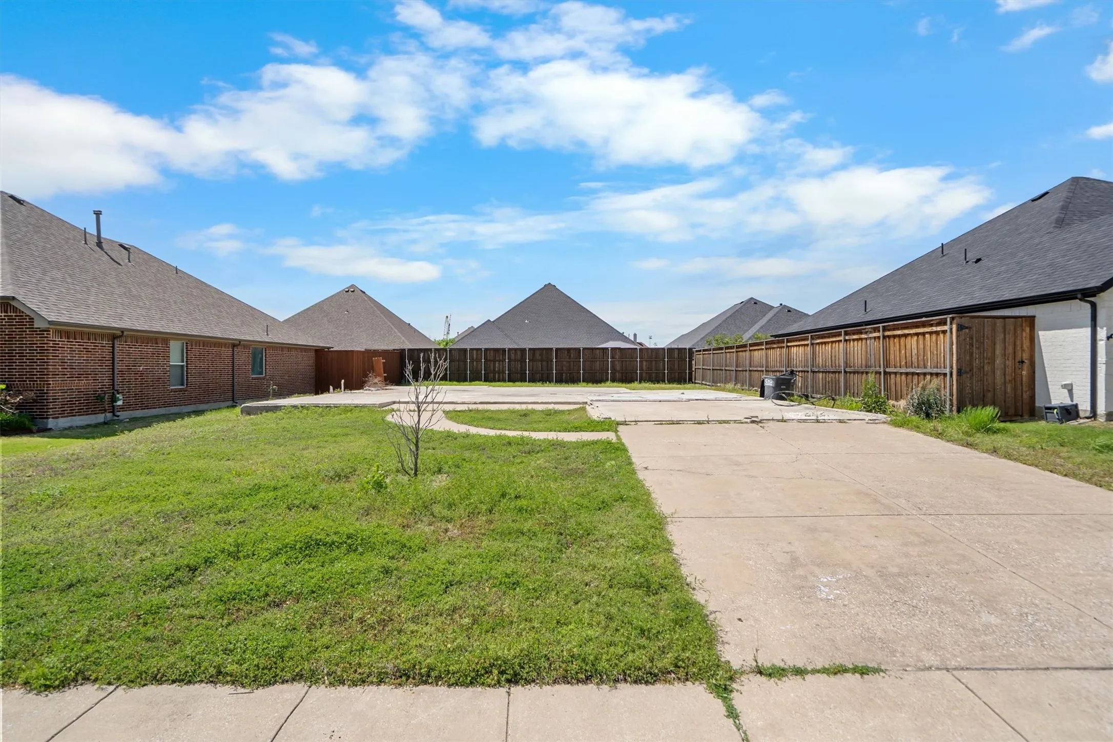 Expansive backyard featuring a concrete patio area, a concrete path, a grass lawn, and a wood privacy fence