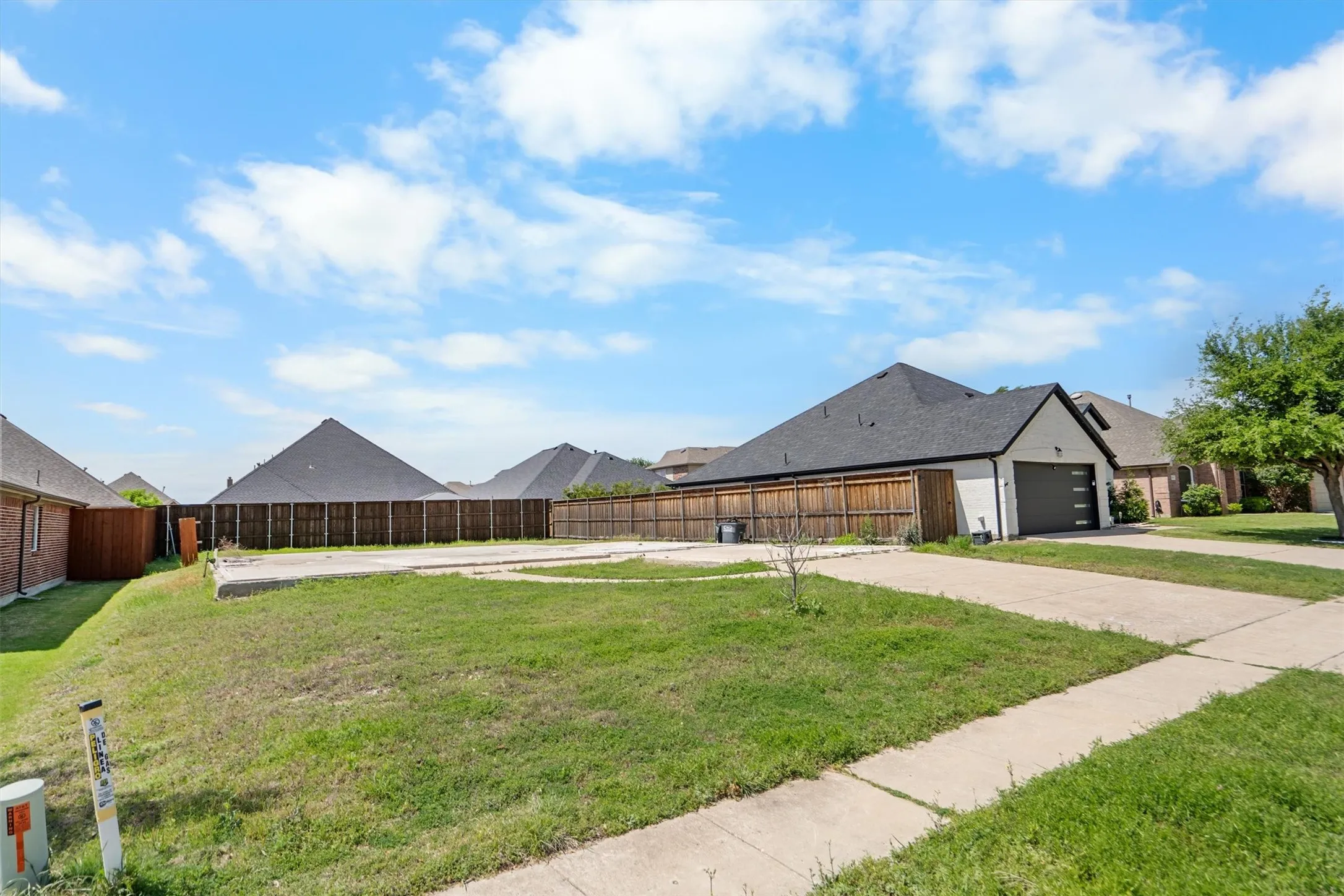 Expansive lot featuring a concrete driveway and sidewalk, surrounded by partial grass coverage