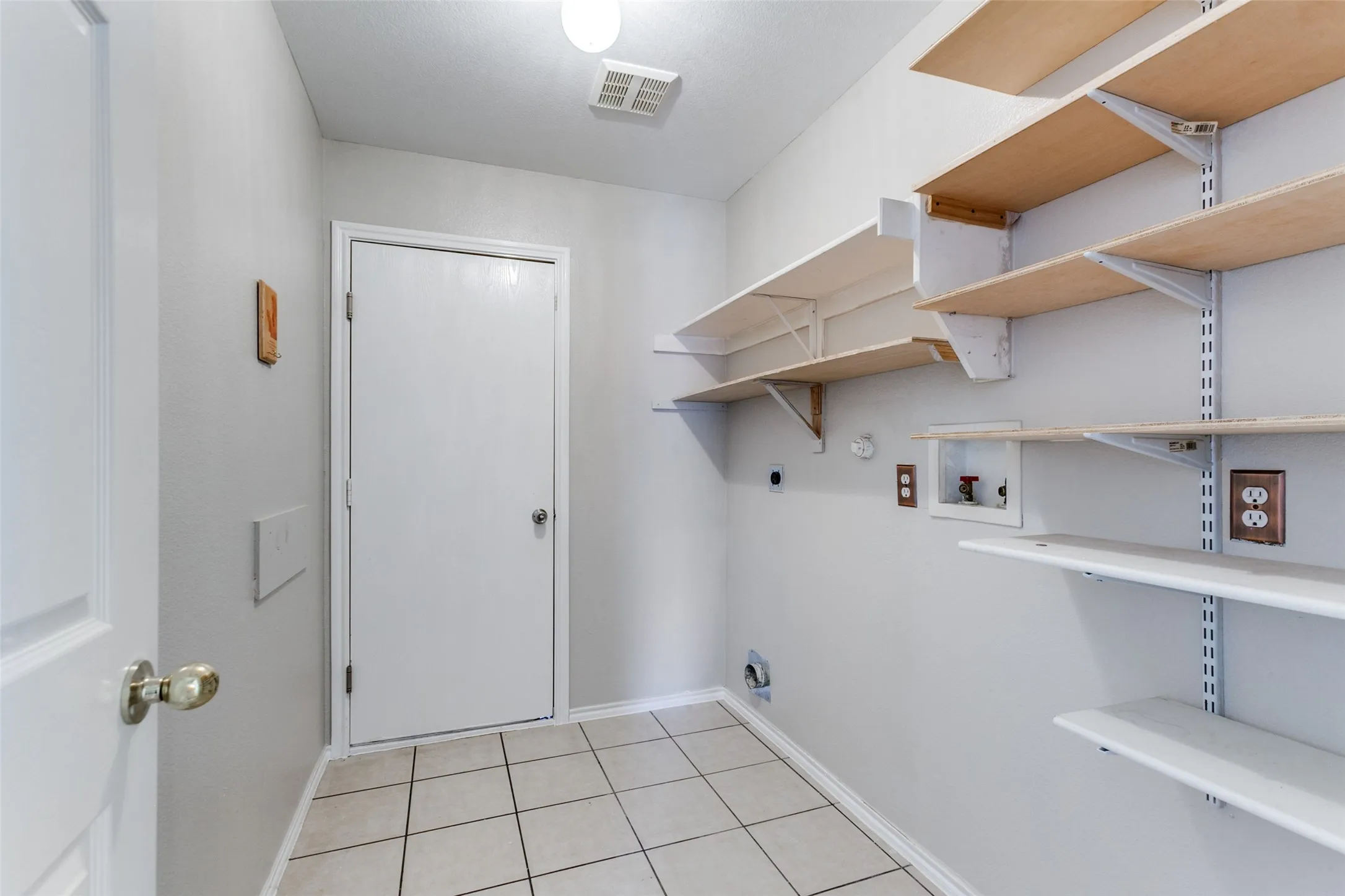 Utility room with white square floor tiles and light gray walls