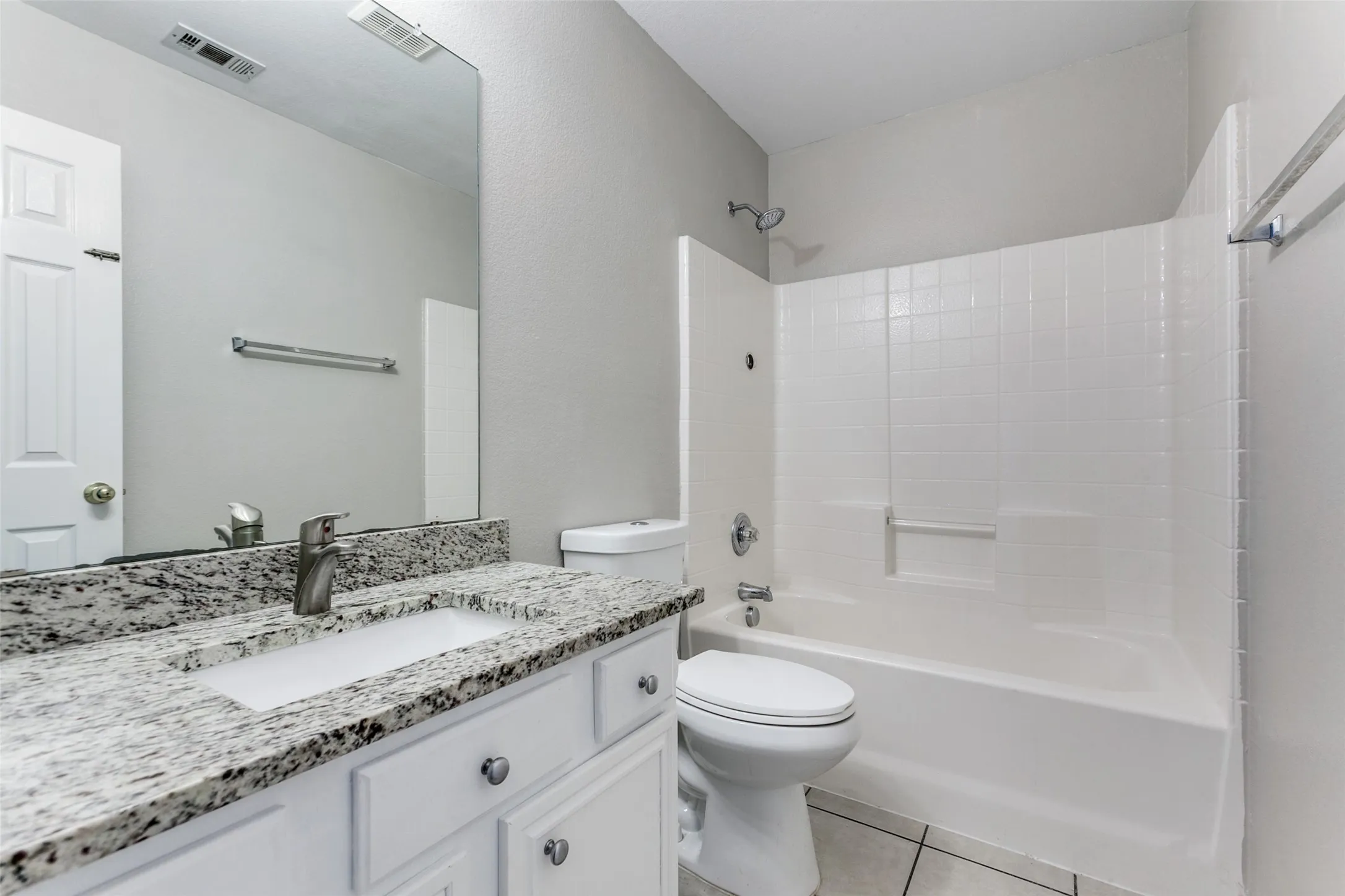 Bathroom featuring a white vanity with a speckled countertop, undermount sink, and brushed nickel faucet