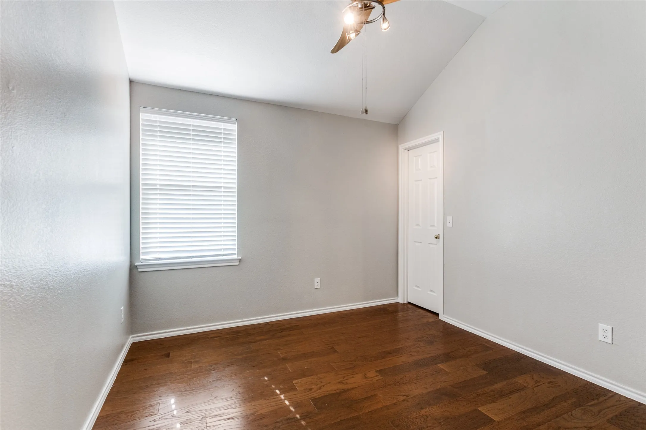 Room featuring a vaulted ceiling and wood-finish flooring