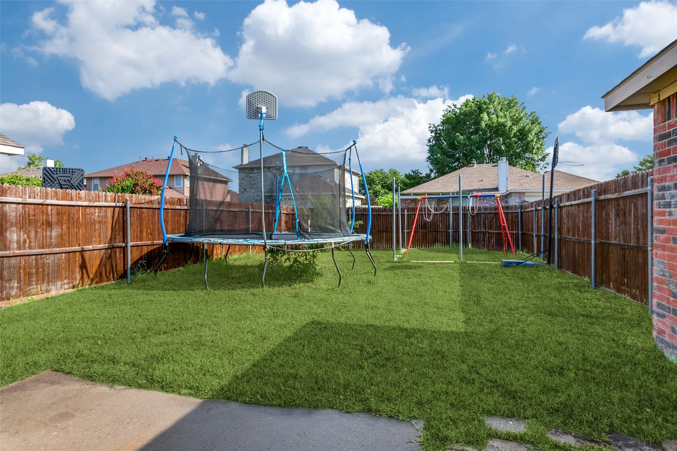Private backyard with mature wood fencing, a verdant lawn, and a concrete patio