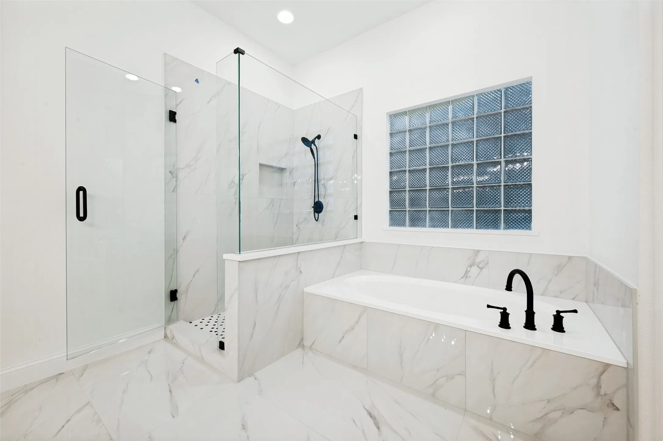 Spacious bathroom featuring a glass-enclosed shower with a built-in niche and a large jetted soaking tub