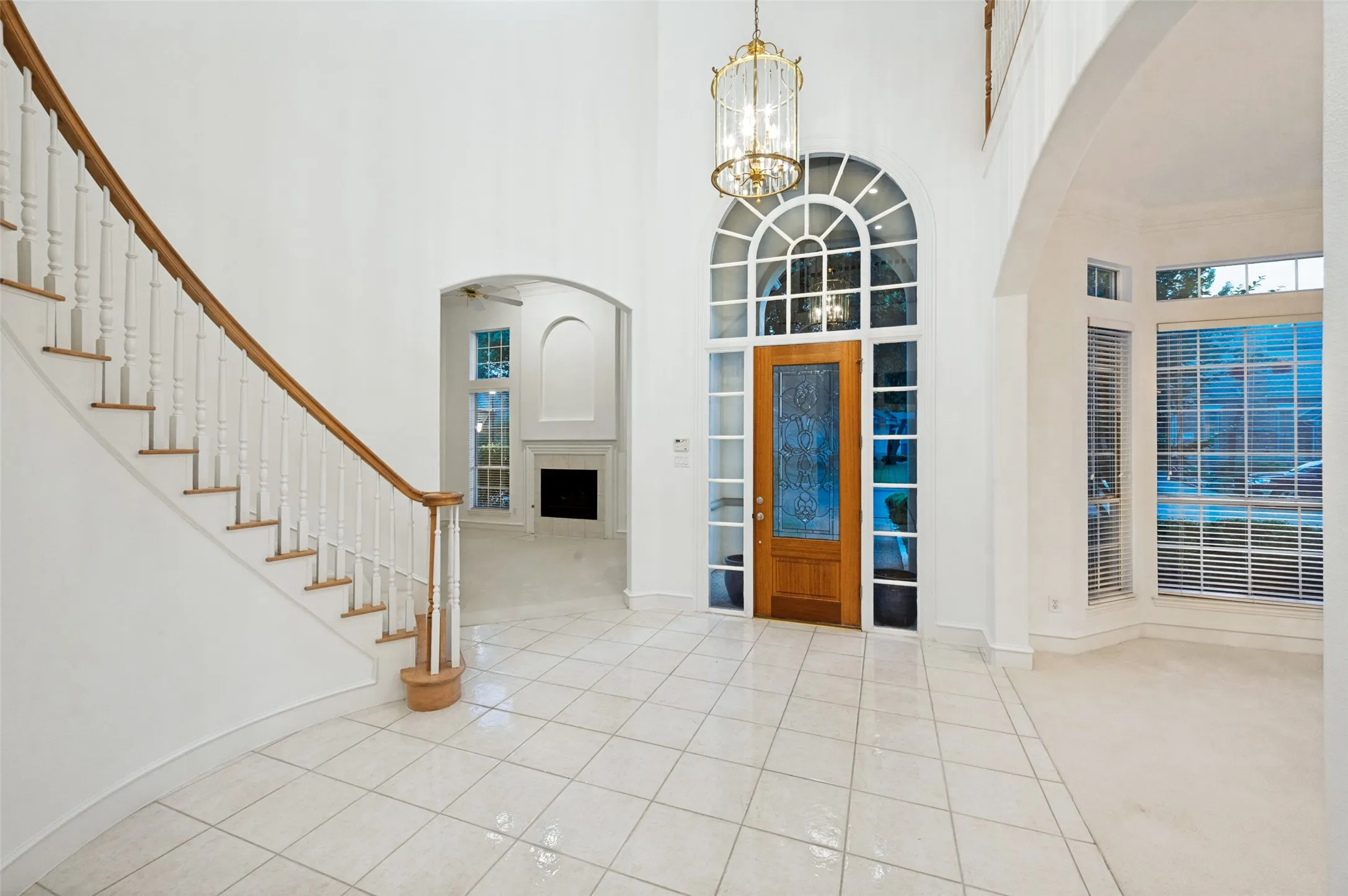 Grand foyer featuring a tile floor, a curved staircase with wood railing, and a vaulted ceiling
