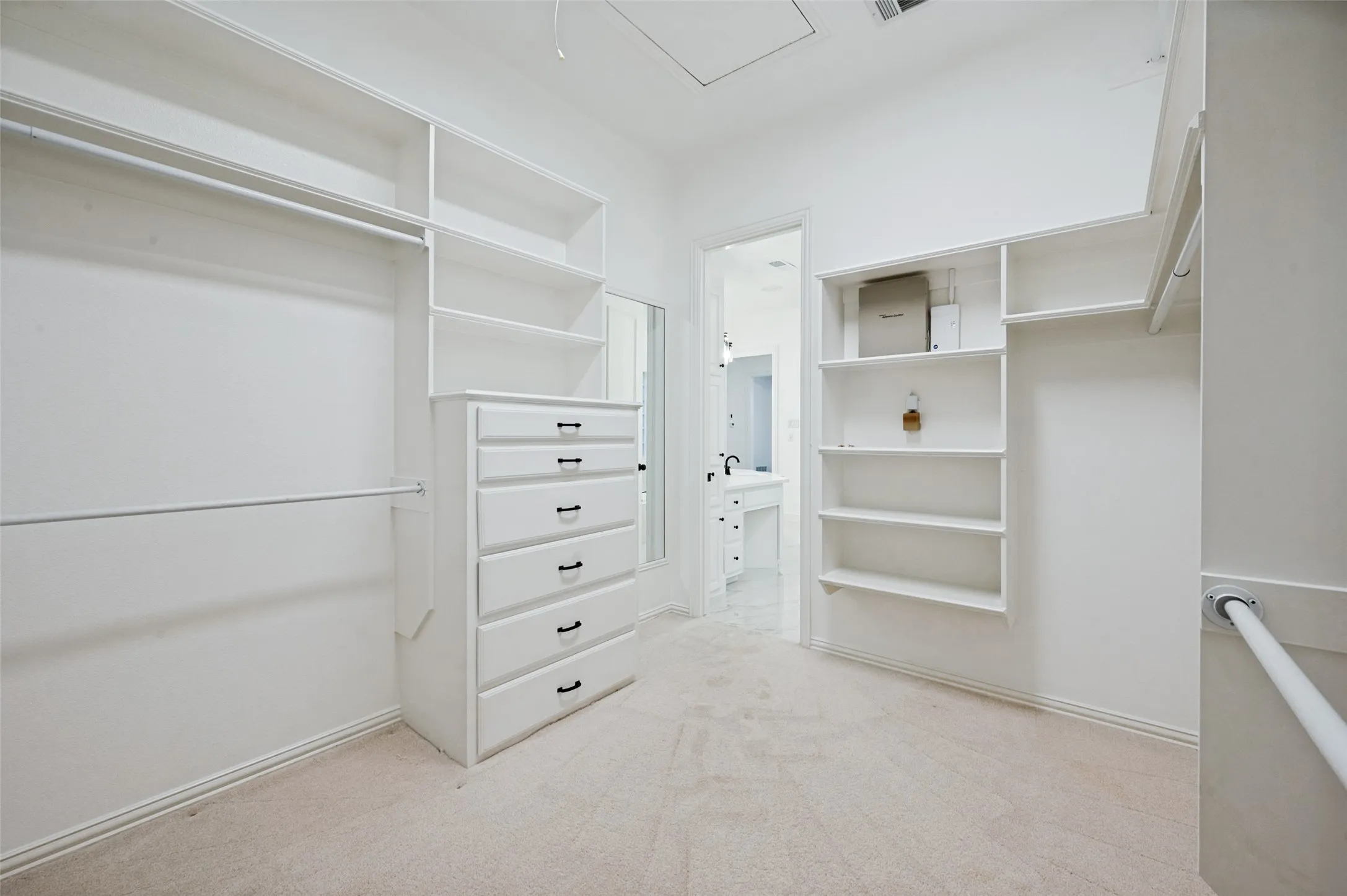 Primary Bedroom Closet- Built-in storage solutions featuring shelving, hanging rods, and a six-drawer dresser