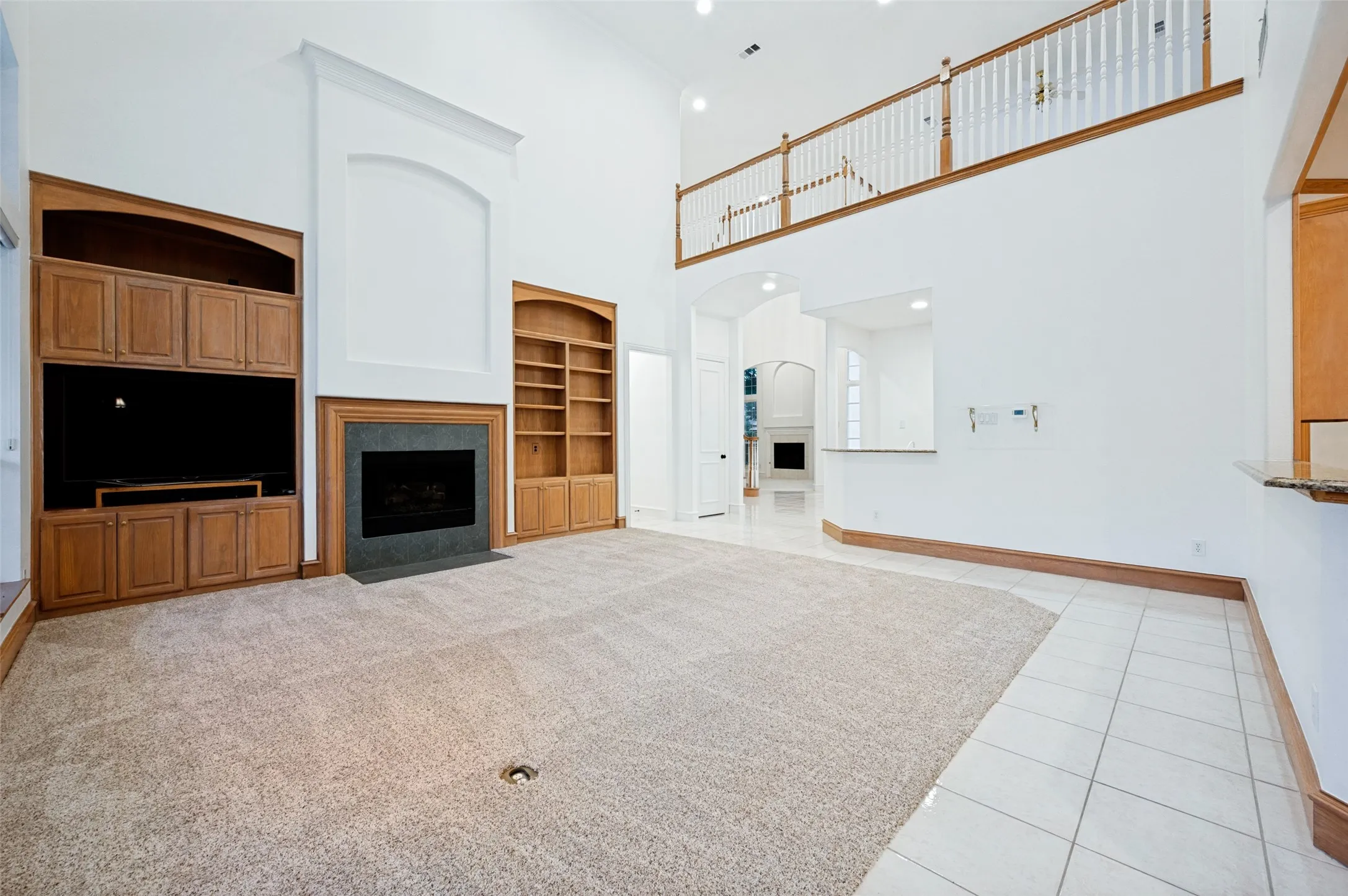 Spacious living room featuring a fireplace with a dark stone surround, custom built-in cabinetry, and a carpeted floor
