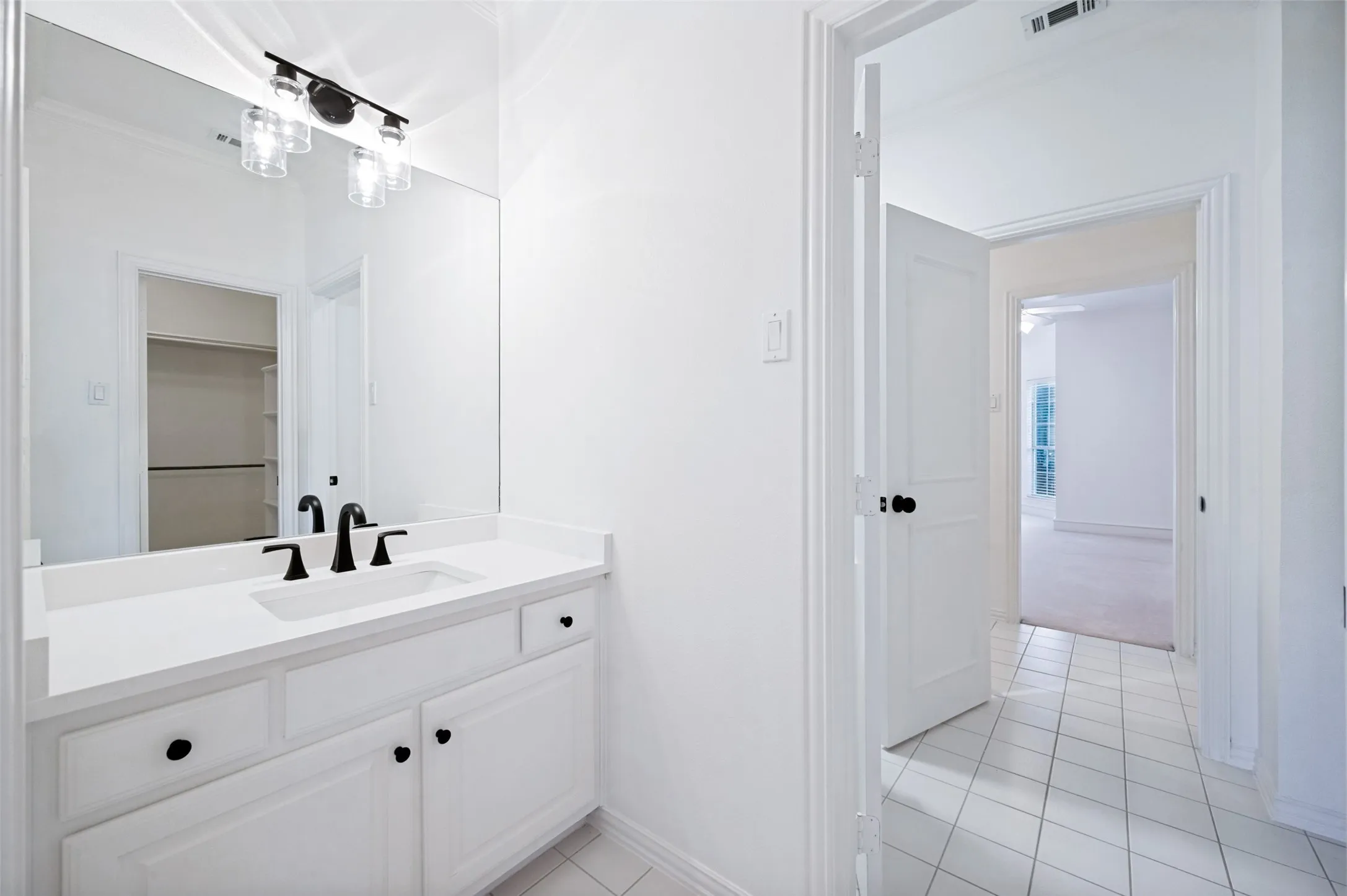 Upstairs Jack & Jill Bath -Vanity with white countertop and integrated sink, matte black faucet, and coordinating light fixture