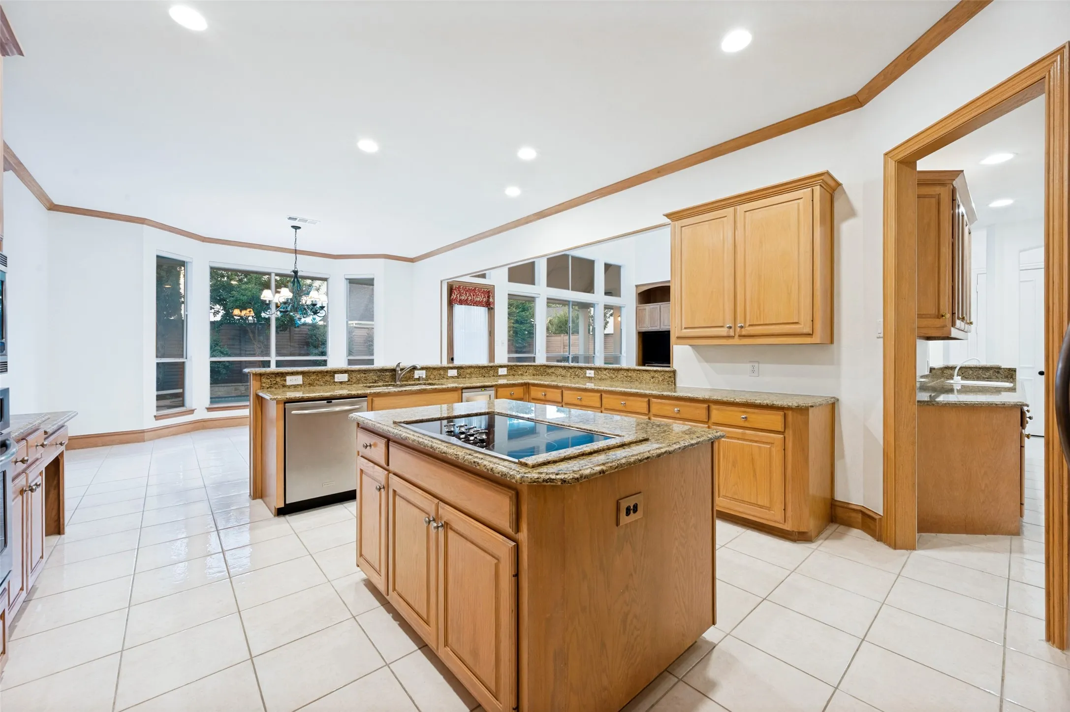 Spacious kitchen featuring an island with an integrated cooktop, stone countertops, and wood cabinetry